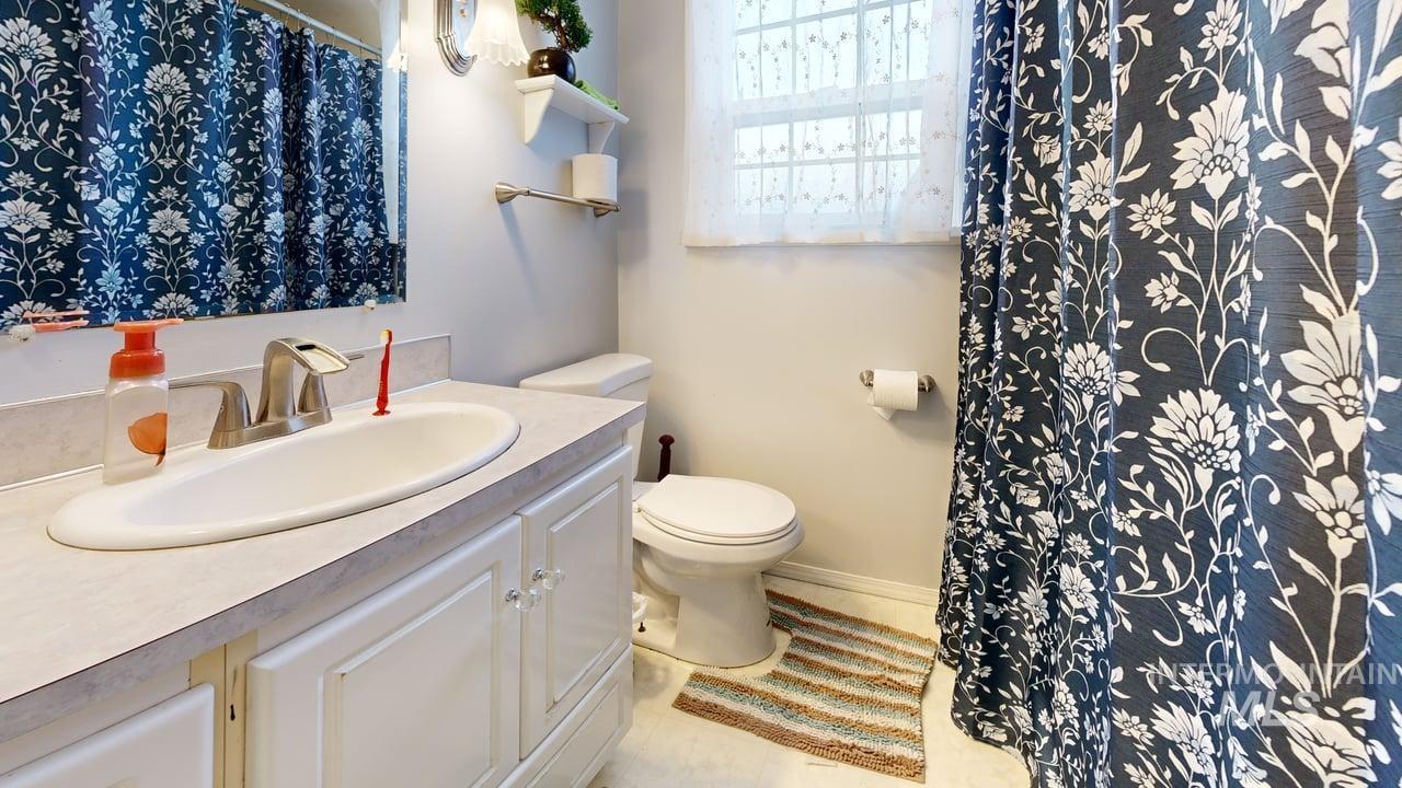 Bathroom featuring a shower with shower curtain, vanity, and light tile patterned floors