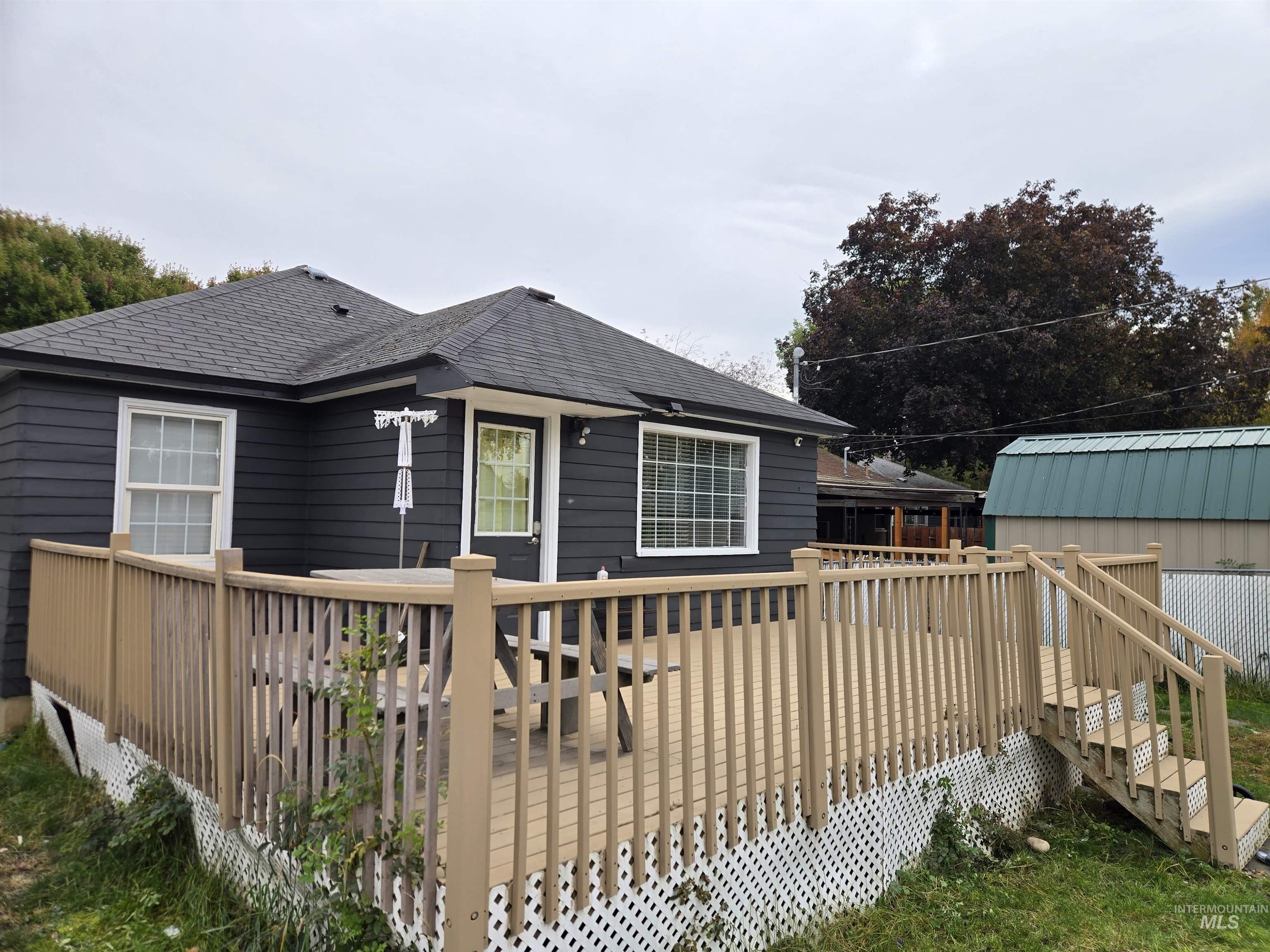 Back of property with a wooden deck and roof with shingles