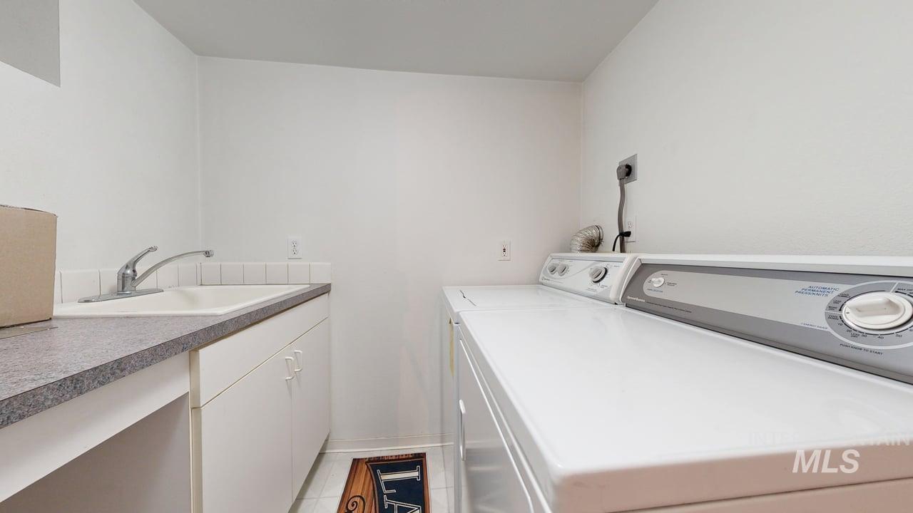Washroom with washing machine and clothes dryer, light tile patterned flooring, and cabinet space