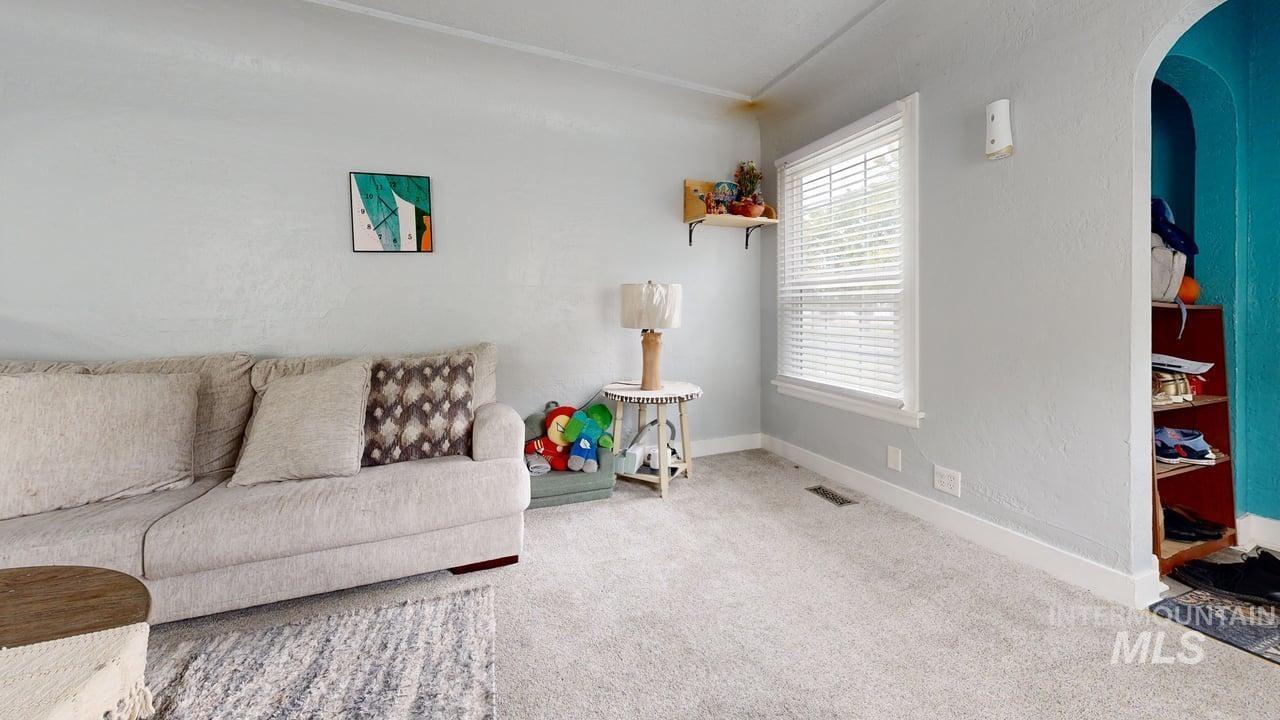 Living area with arched walkways, carpet, and a textured wall