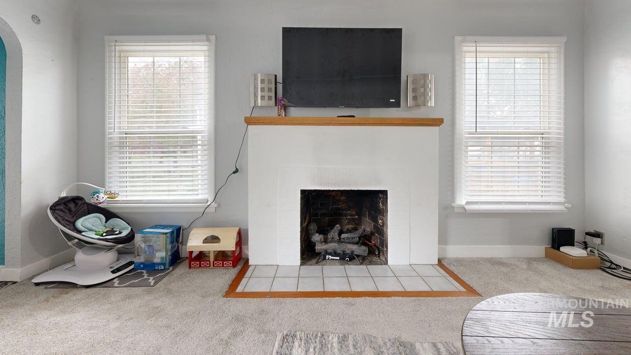 Carpeted living room featuring a fireplace with flush hearth and arched walkways