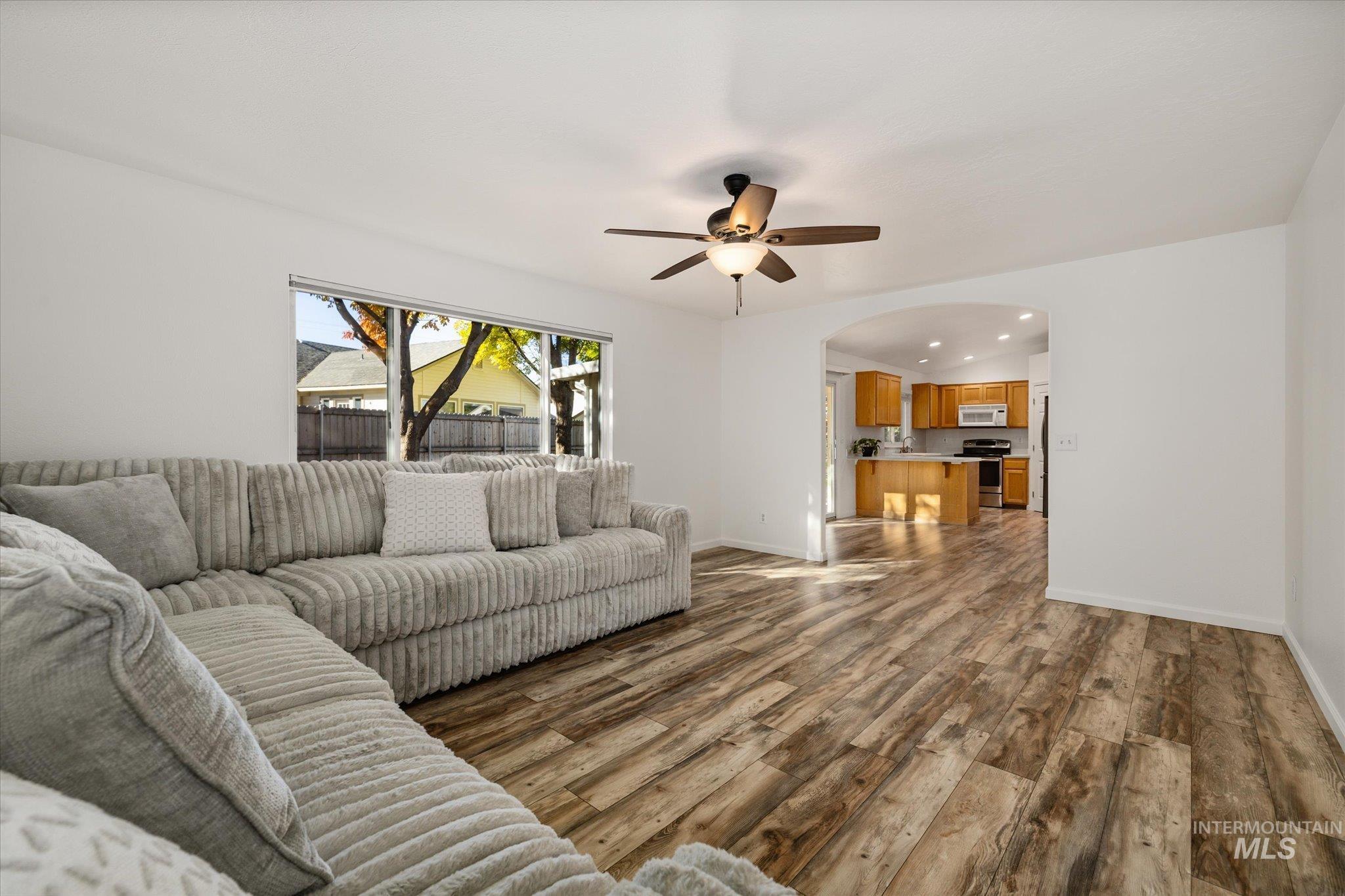 Living room featuring arched walkways, recessed lighting, dark wood-style flooring, and ceiling fan