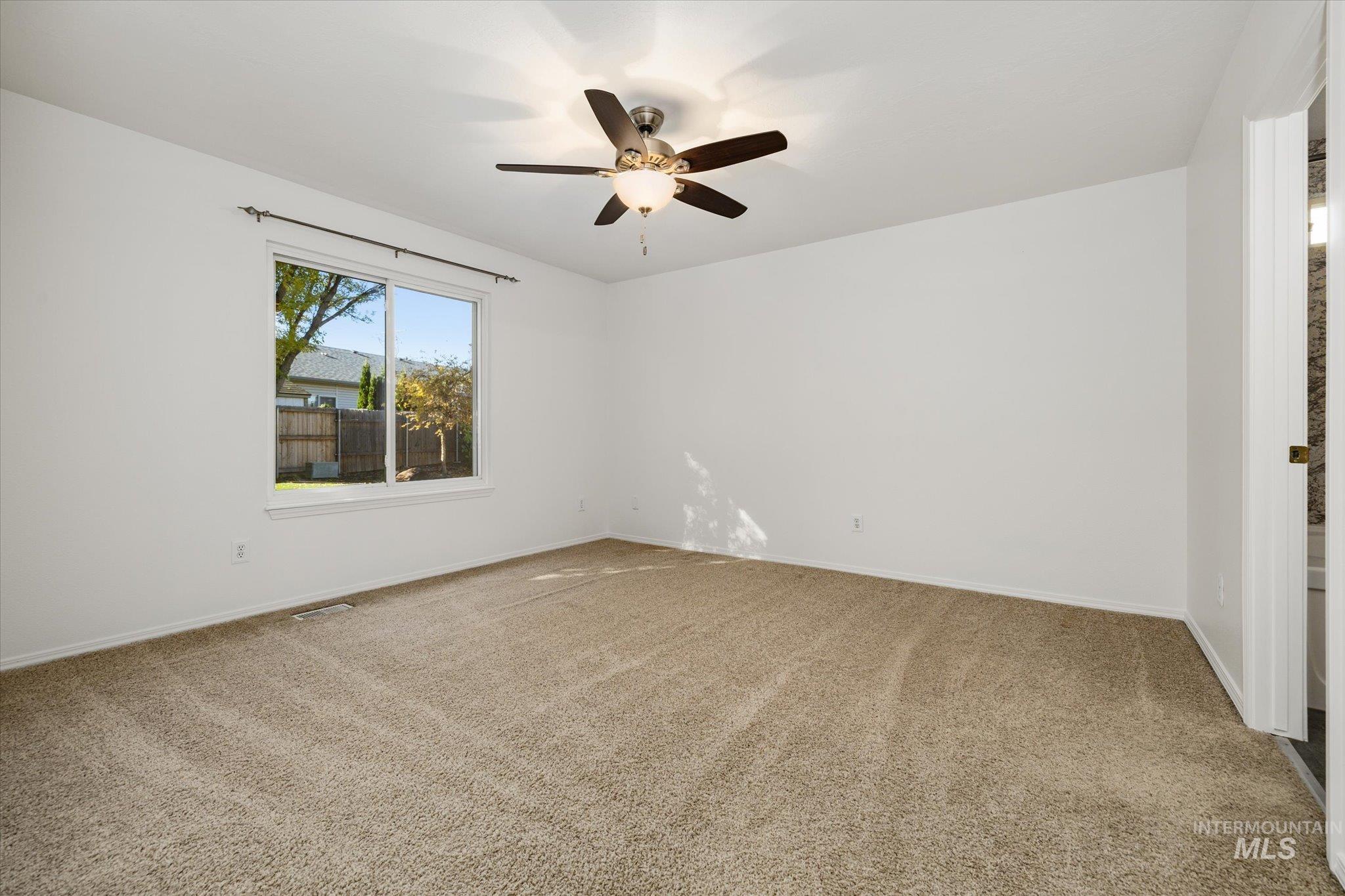 Unfurnished room with light colored carpet and a ceiling fan