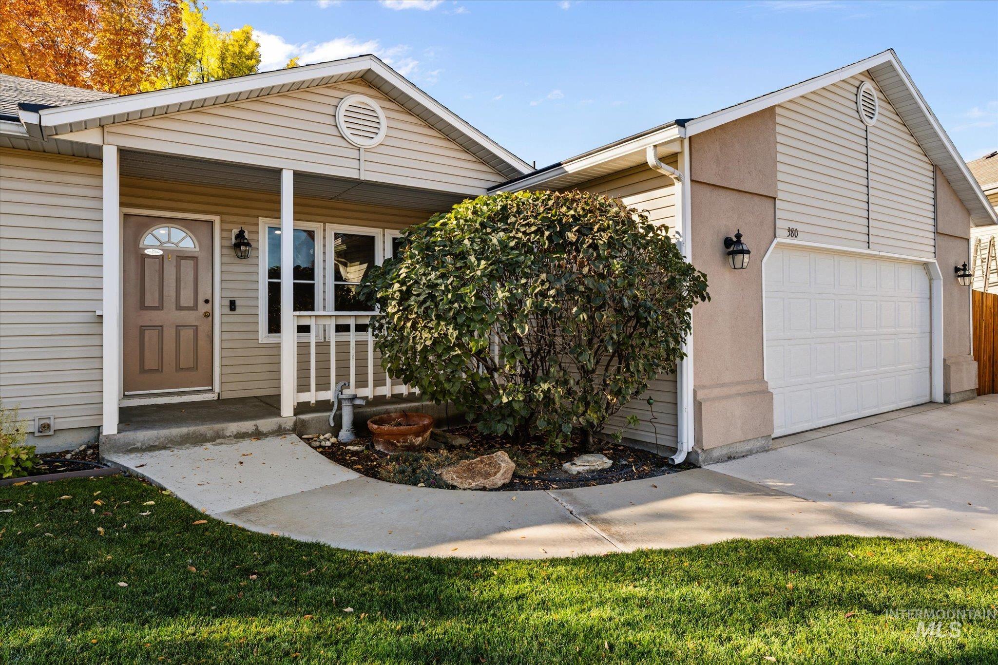 View of front facade with covered porch, an attached garage, a front lawn, and driveway