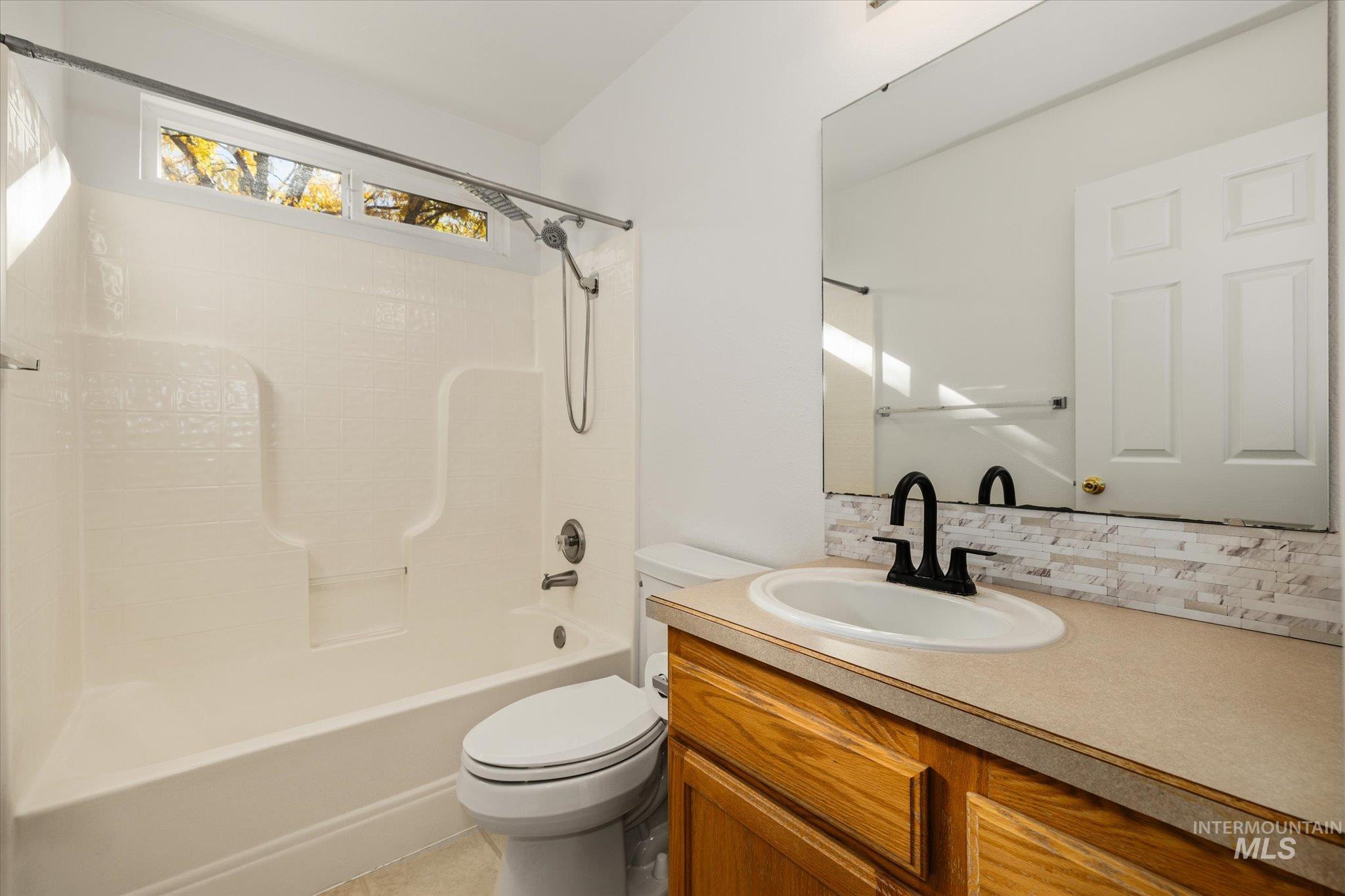 Full bathroom featuring shower / bath combination, vanity, backsplash, and light tile patterned flooring
