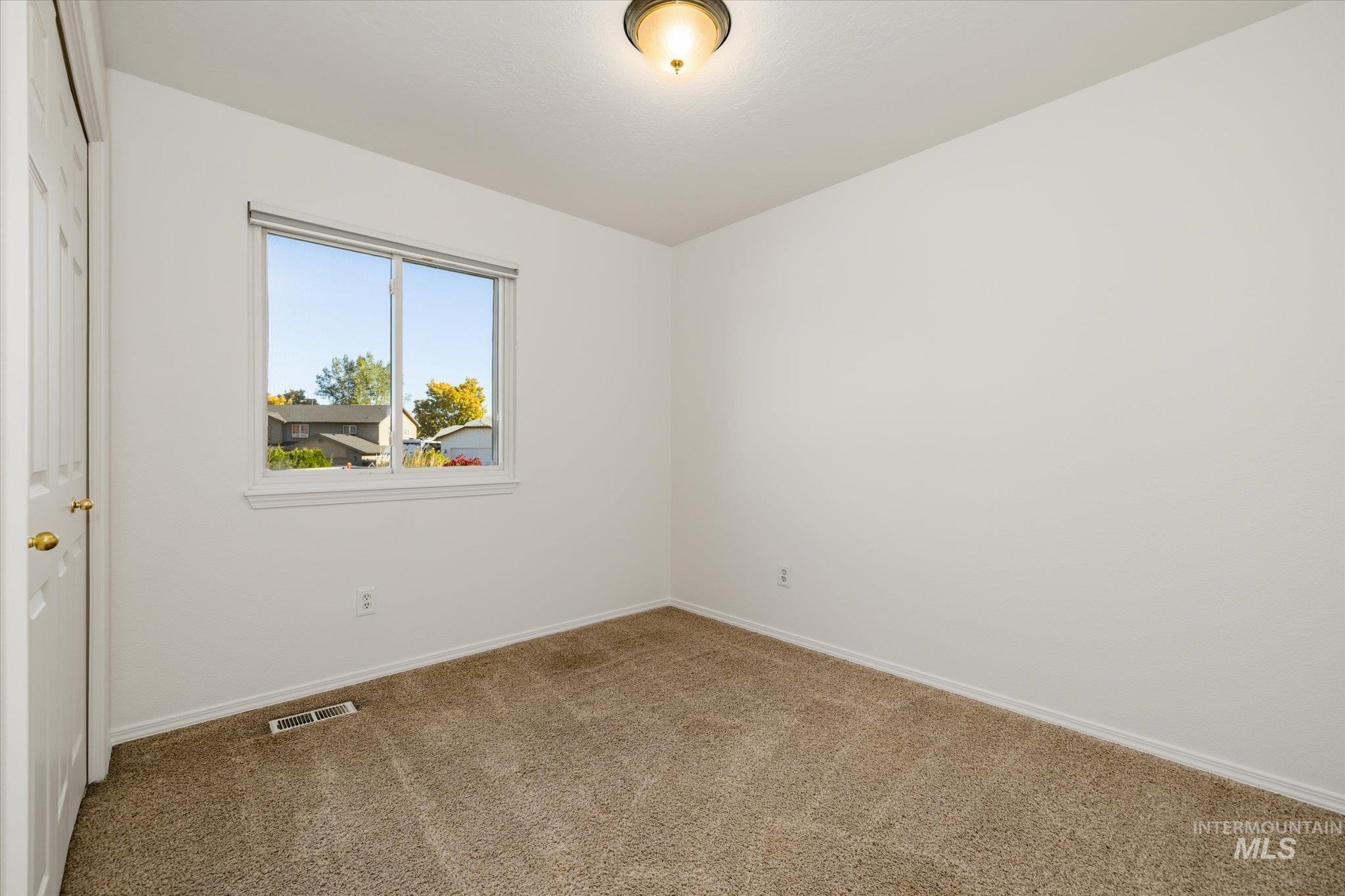 Carpeted spare room featuring baseboards