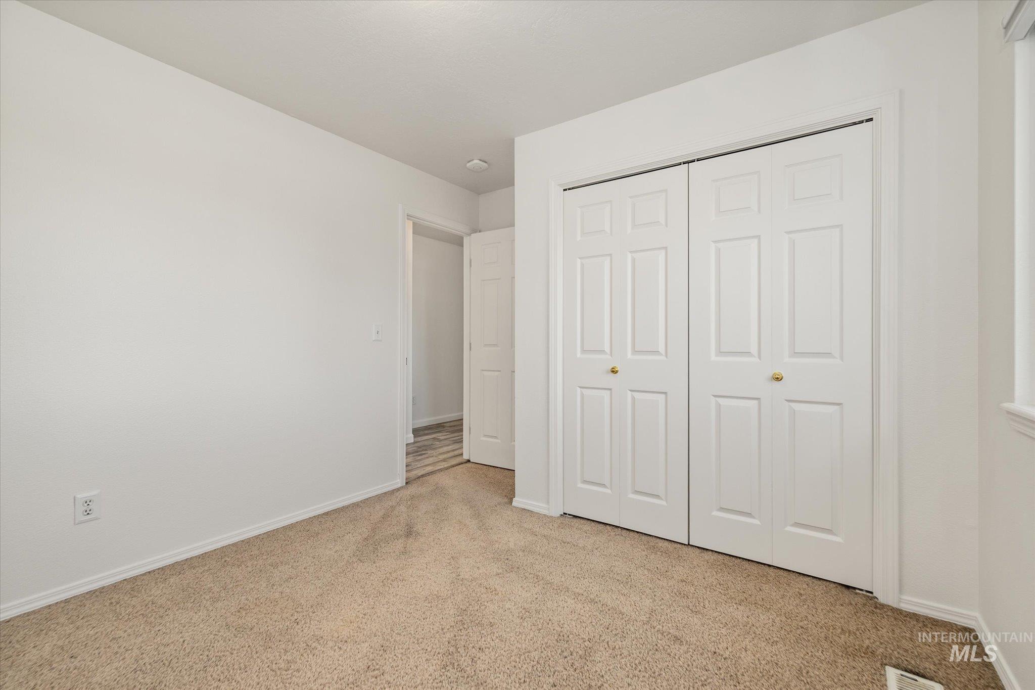 Unfurnished bedroom with light colored carpet and a closet