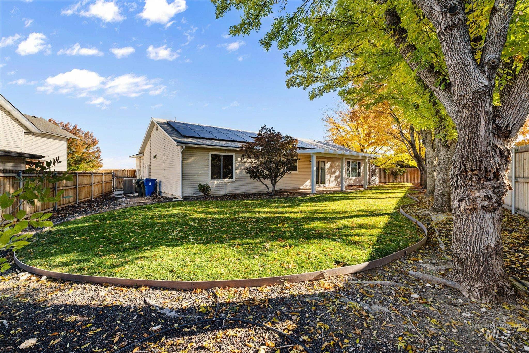 Rear view of property with a fenced backyard and roof mounted solar panels