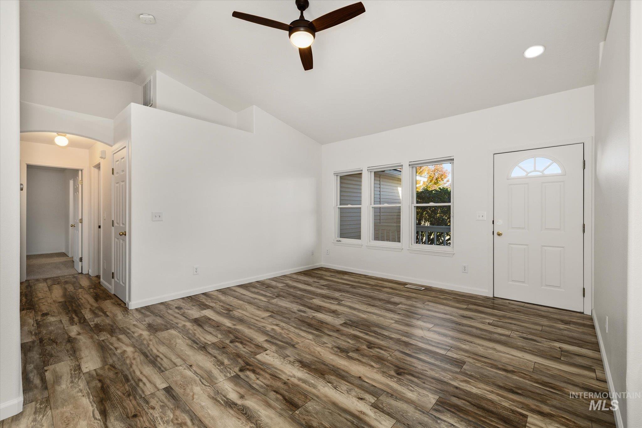 Foyer entrance featuring dark wood-type flooring, a ceiling fan, arched walkways, vaulted ceiling, and recessed lighting