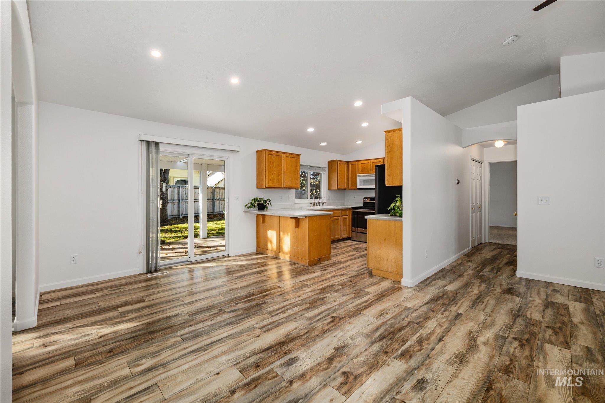 Kitchen with open floor plan, light countertops, recessed lighting, lofted ceiling, and light wood-style floors