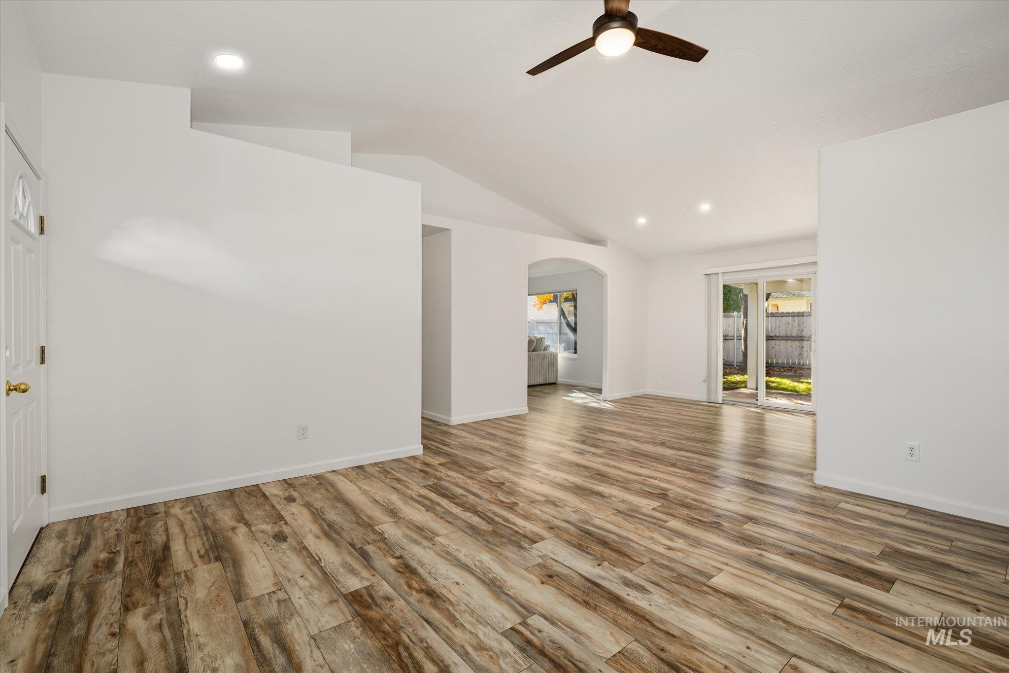 Unfurnished living room featuring recessed lighting, vaulted ceiling, light wood-type flooring, ceiling fan, and arched walkways
