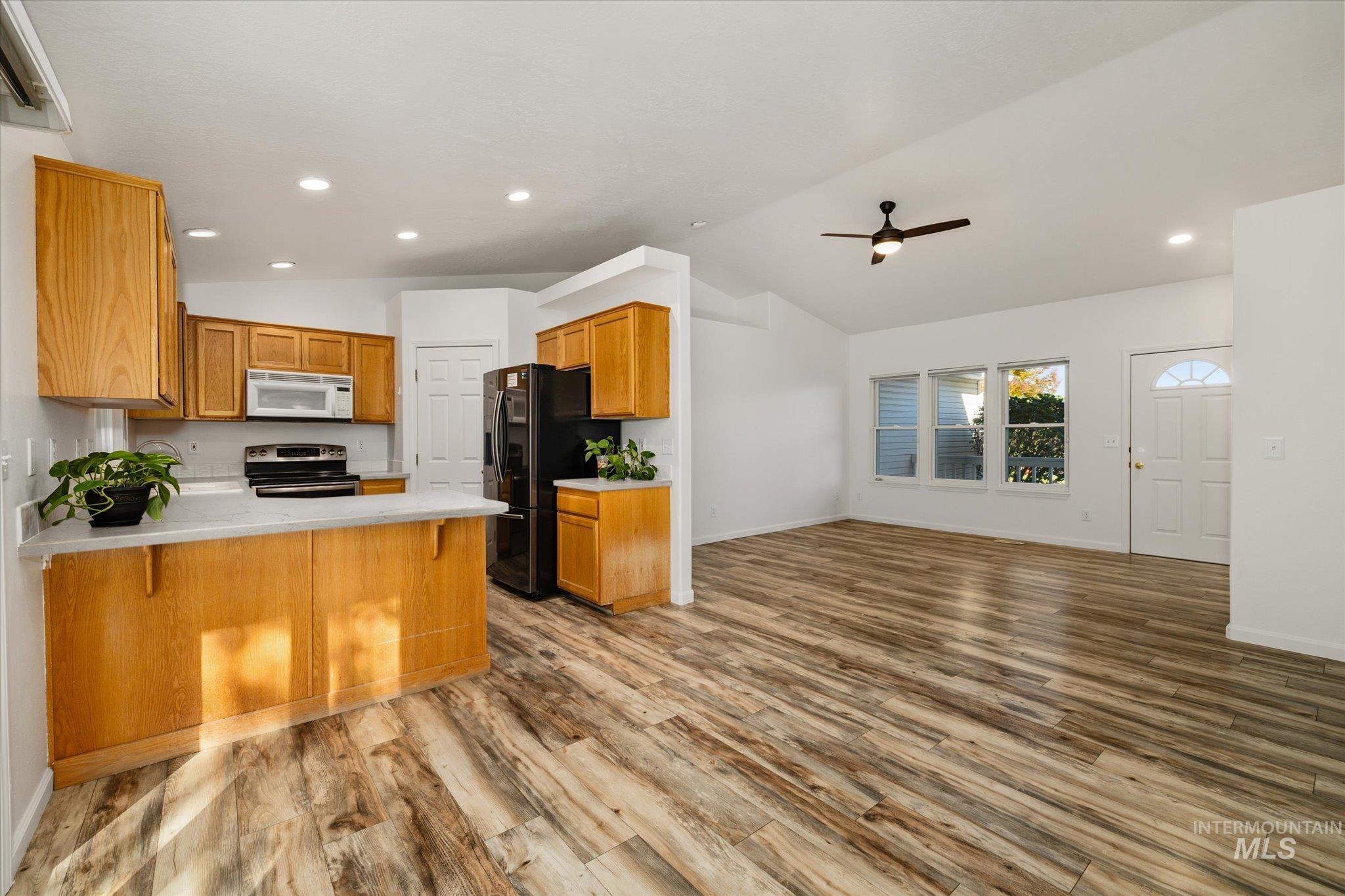 Kitchen with a peninsula, vaulted ceiling, recessed lighting, open floor plan, and a kitchen breakfast bar
