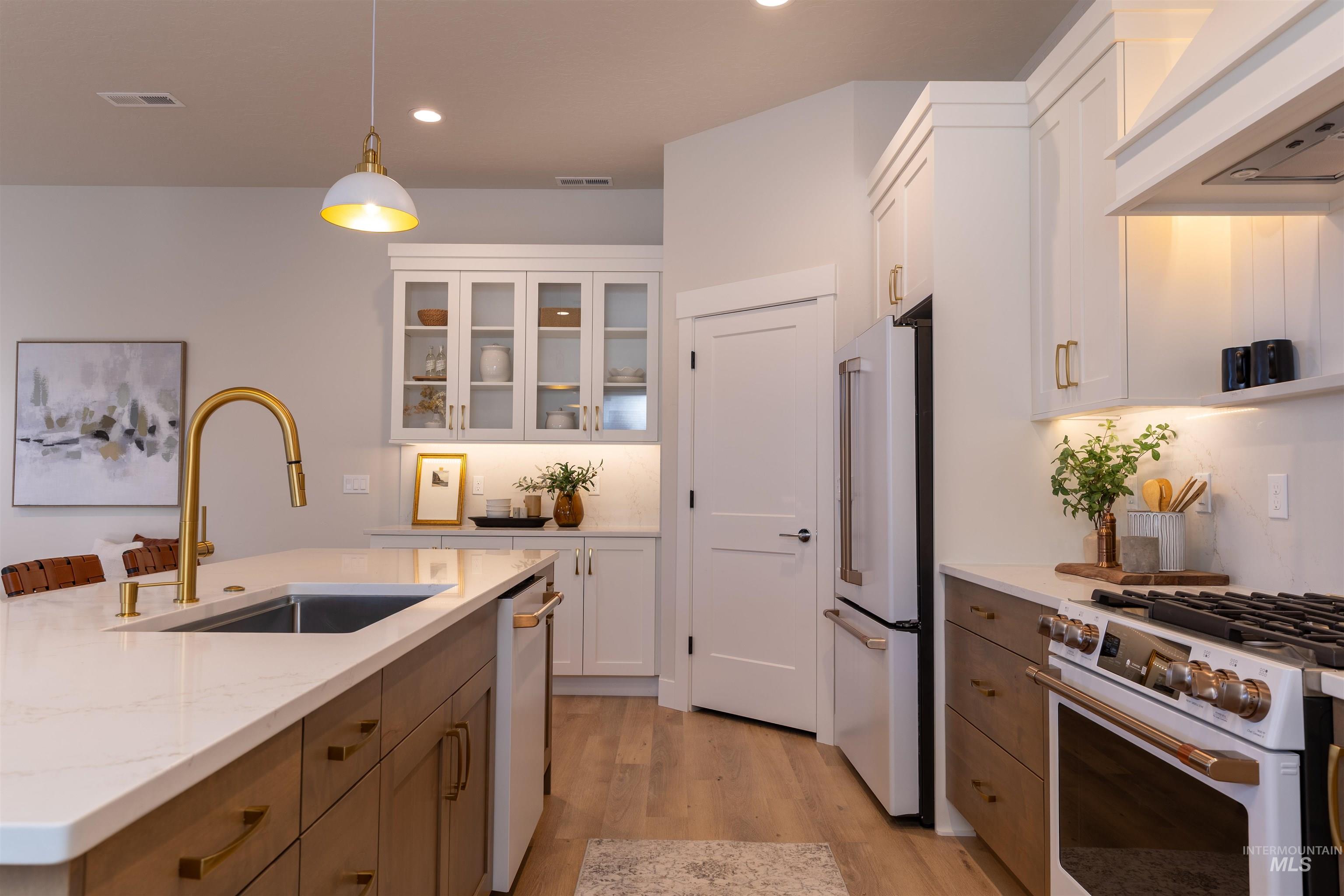 Kitchen with hanging light fixtures, premium appliances, white cabinetry, and recessed lighting