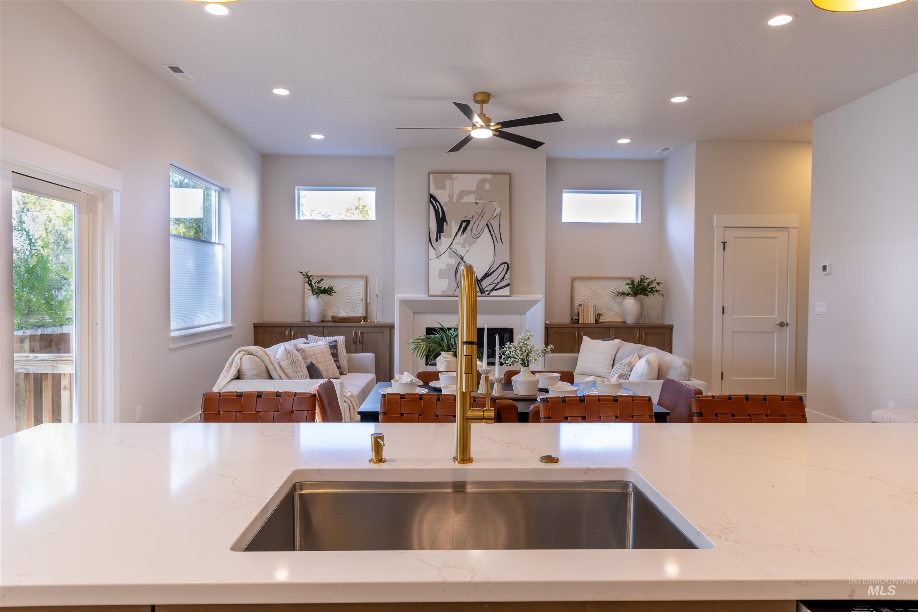 Kitchen with open floor plan, ceiling fan, light stone countertops, recessed lighting, and a fireplace