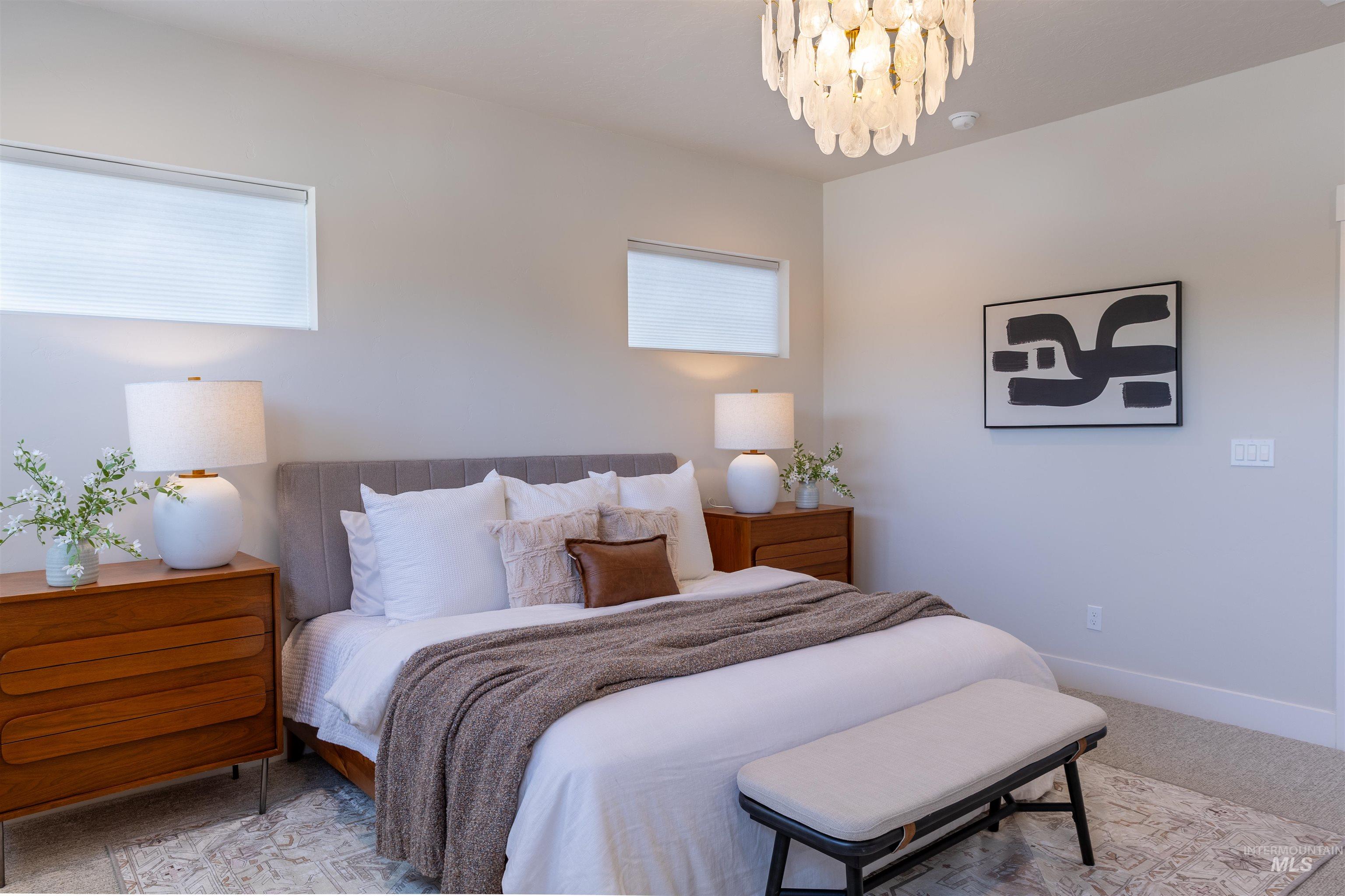 Carpeted bedroom with baseboards and a chandelier