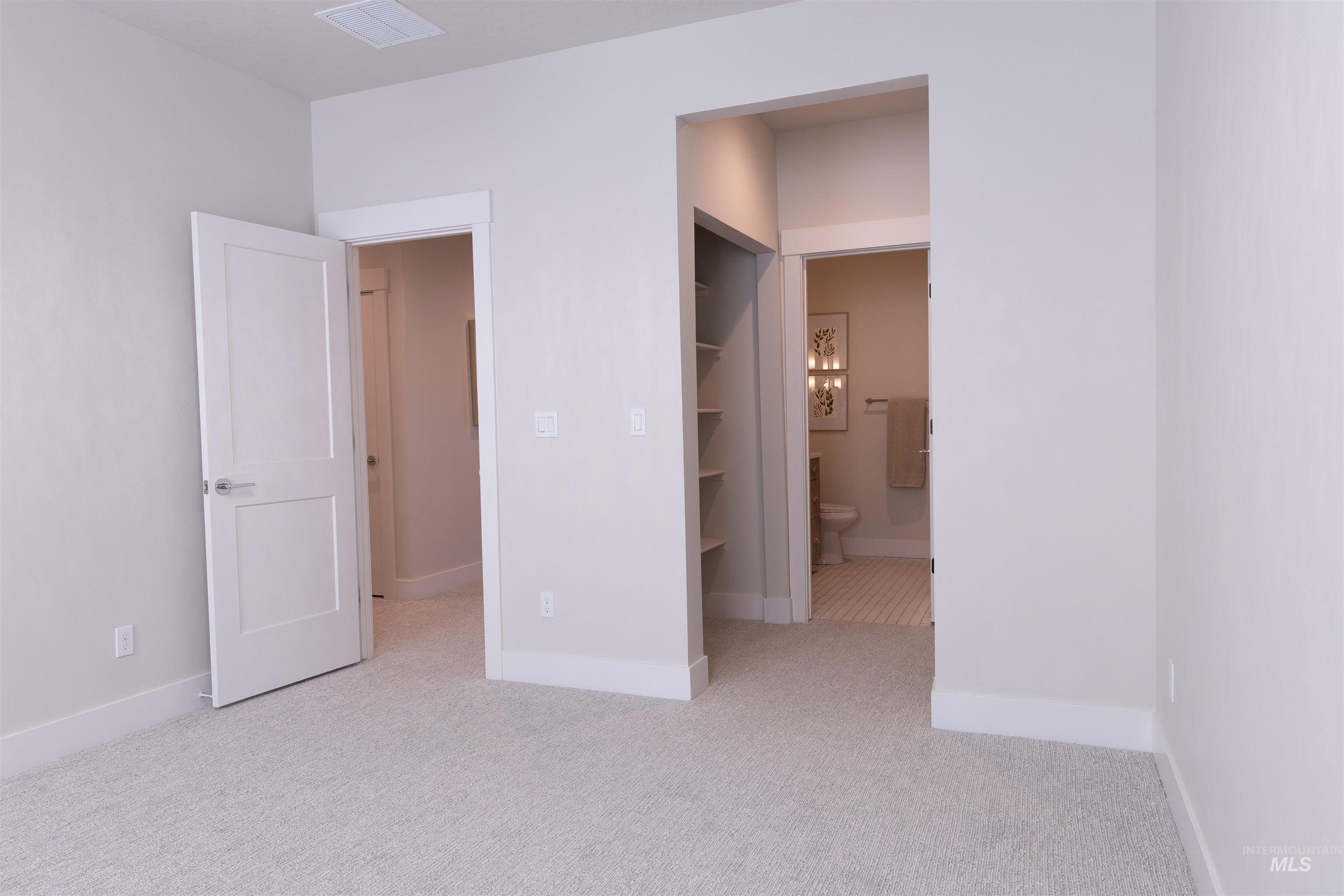 Unfurnished bedroom with light carpet and ensuite bathroom
