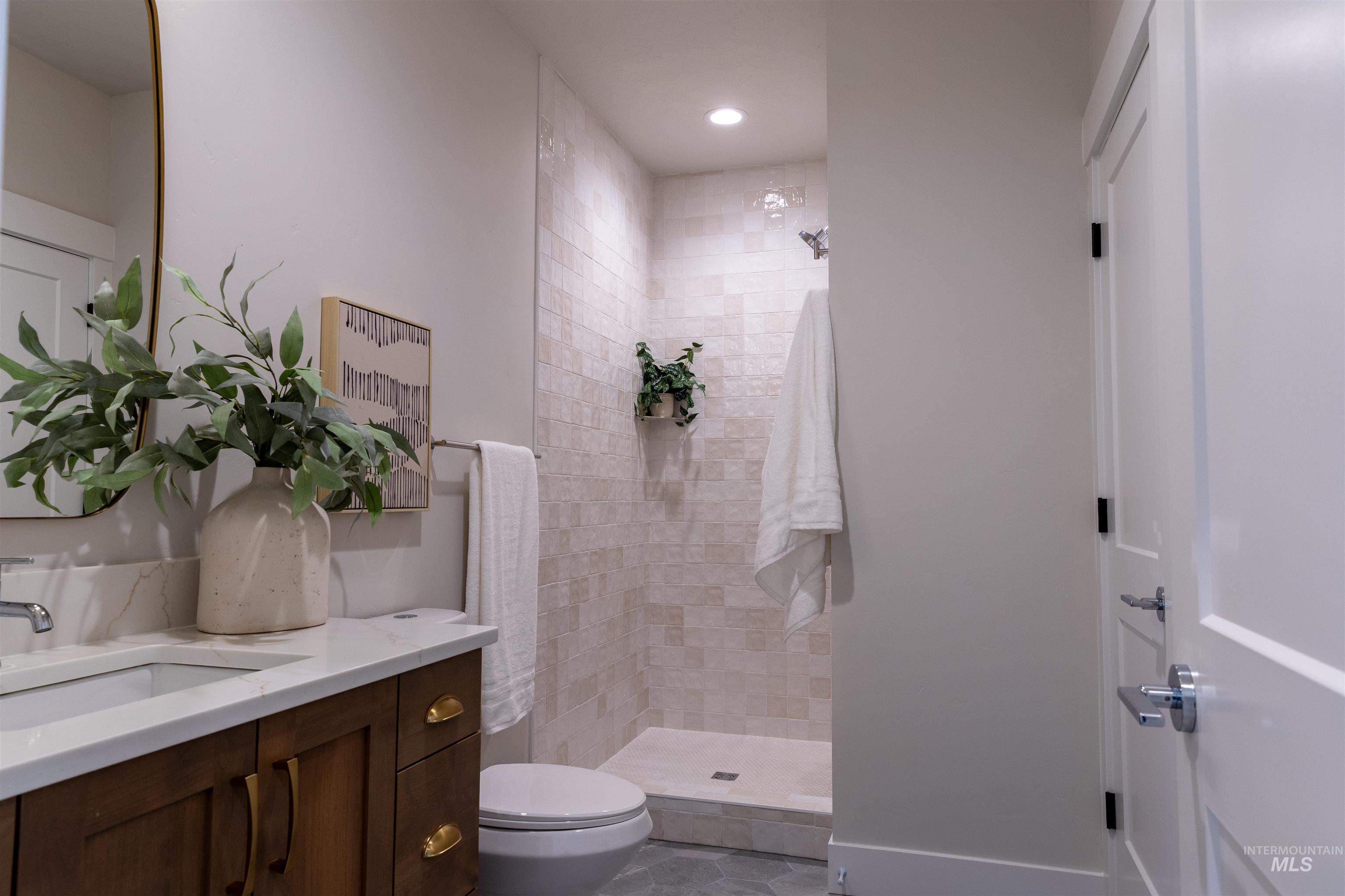 Full bath with vanity, tiled shower, recessed lighting, and light tile patterned flooring
