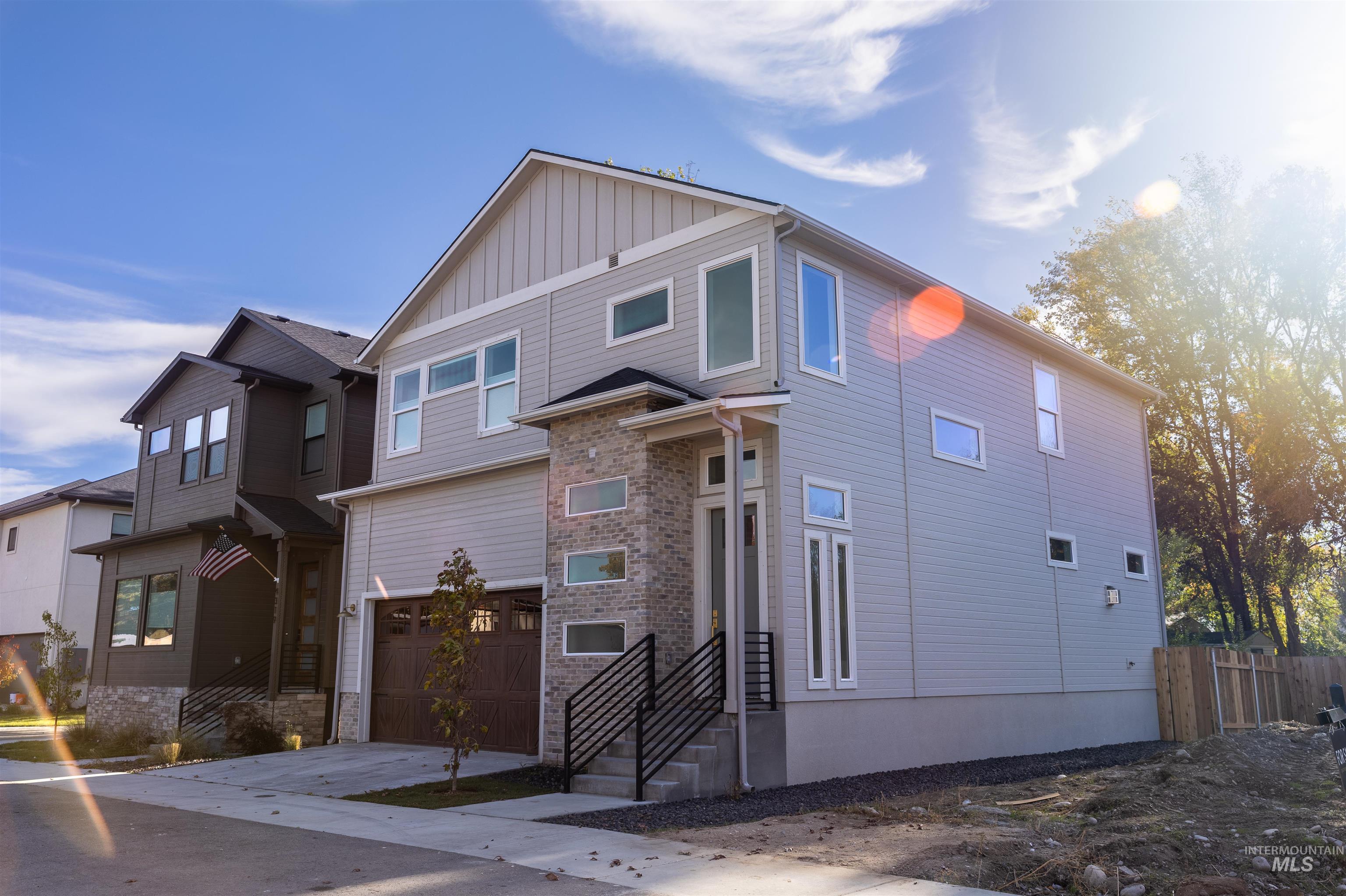 View of front of house featuring a garage, driveway, board and batten siding, and stone siding