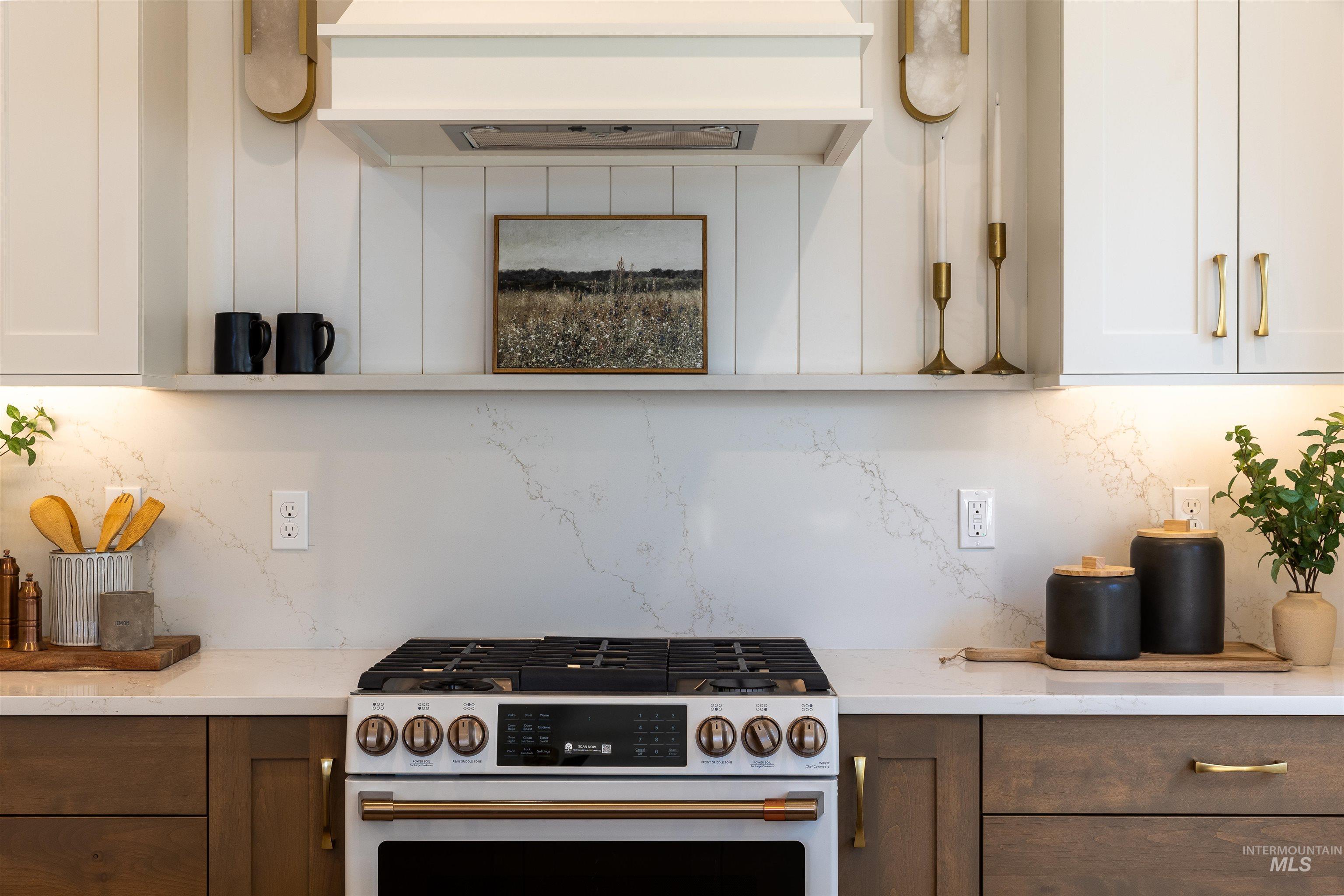 Kitchen featuring tasteful backsplash, high end white range oven, under cabinet range hood, and white cabinetry