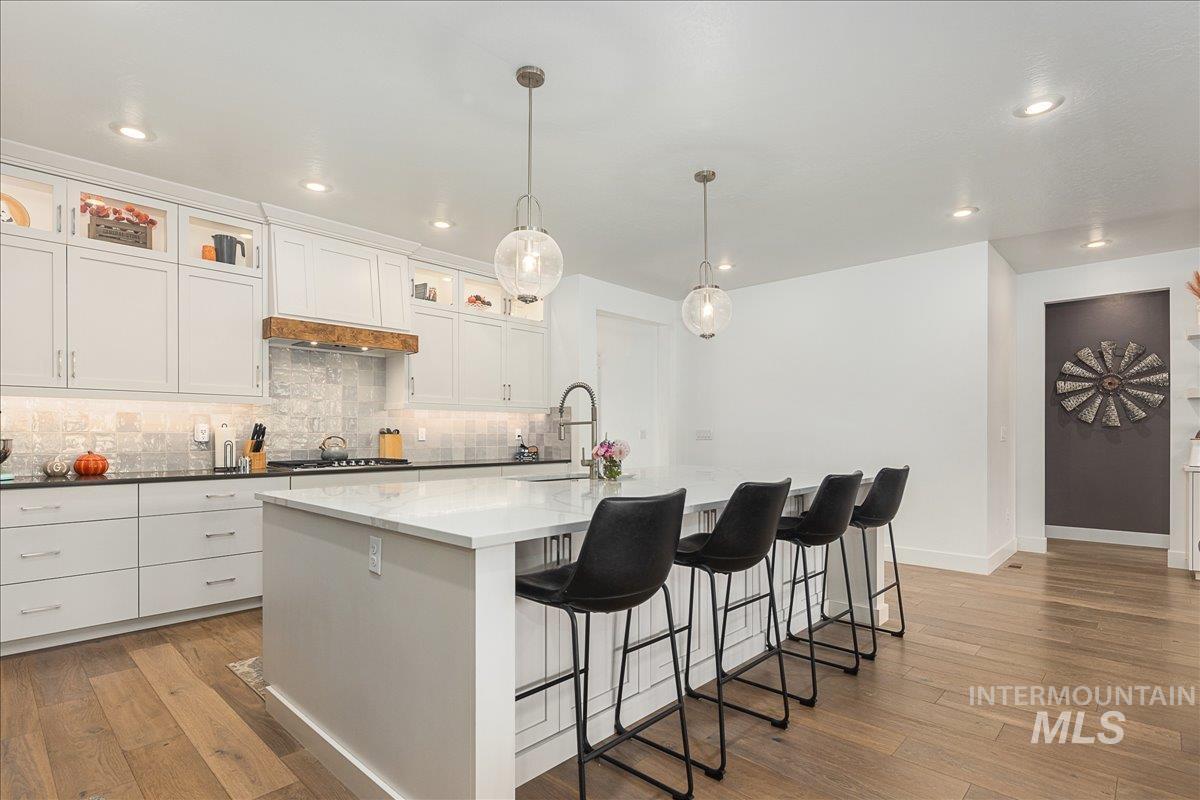 Kitchen featuring white cabinetry, a kitchen bar, light wood finished floors, hanging light fixtures, and recessed lighting