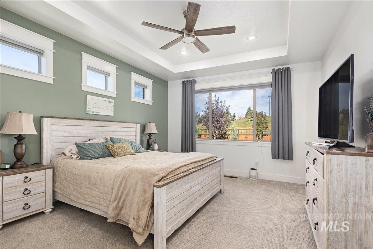 Bedroom with a tray ceiling, light colored carpet, a ceiling fan, and recessed lighting