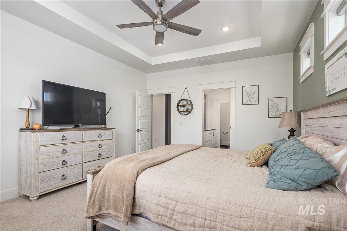 Carpeted bedroom featuring a tray ceiling, ceiling fan, connected bathroom, and recessed lighting