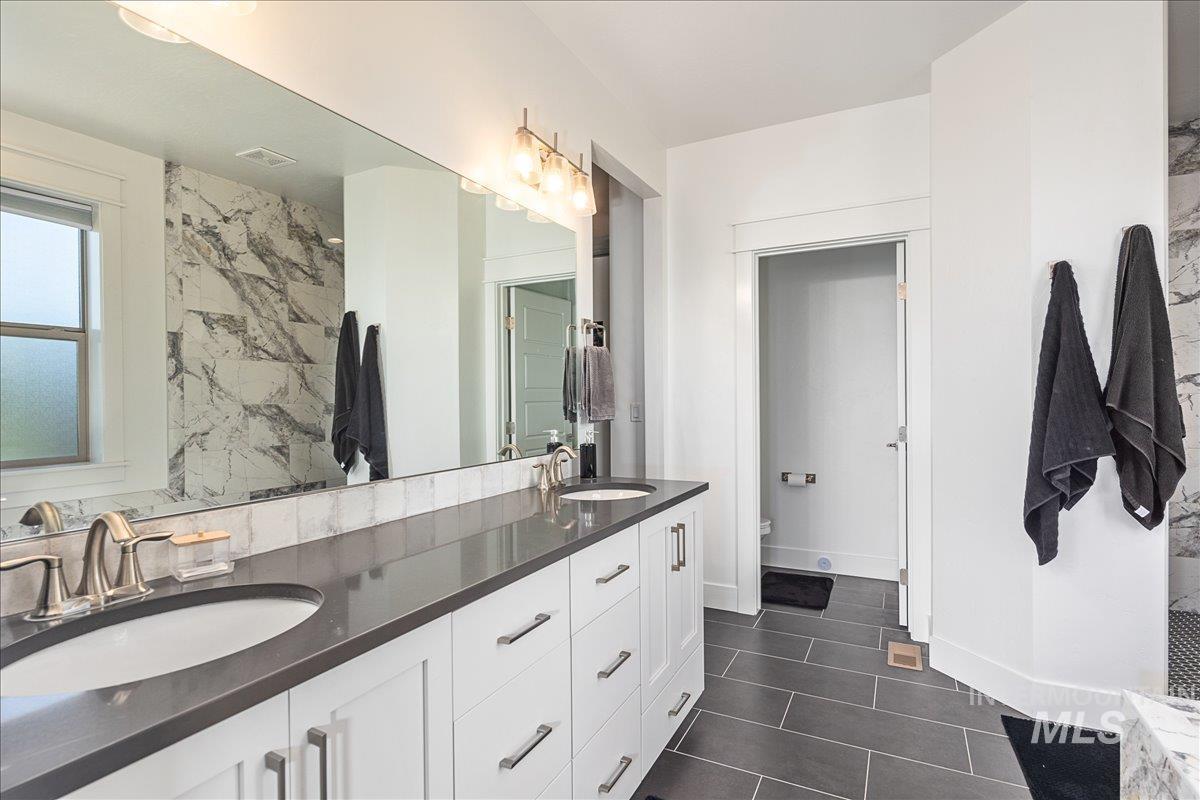 Bathroom featuring double vanity and dark tile patterned floors