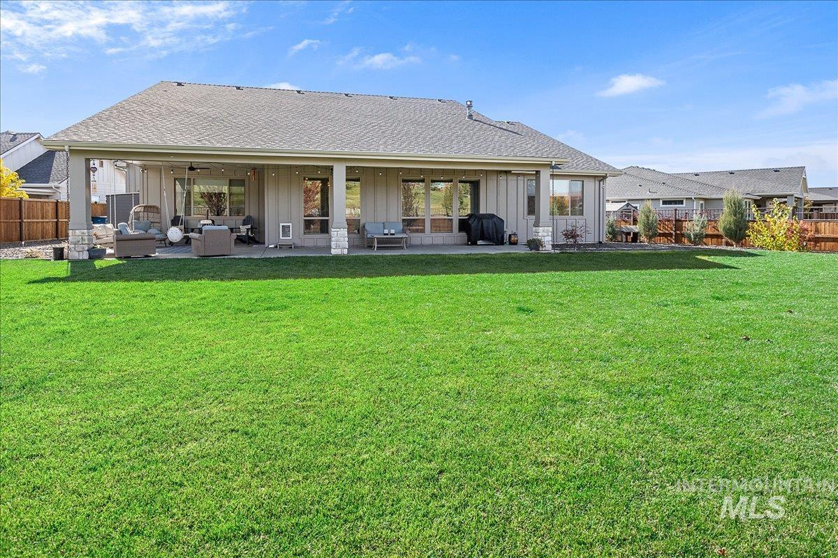 Back of property with a patio, a ceiling fan, a fenced backyard, and board and batten siding
