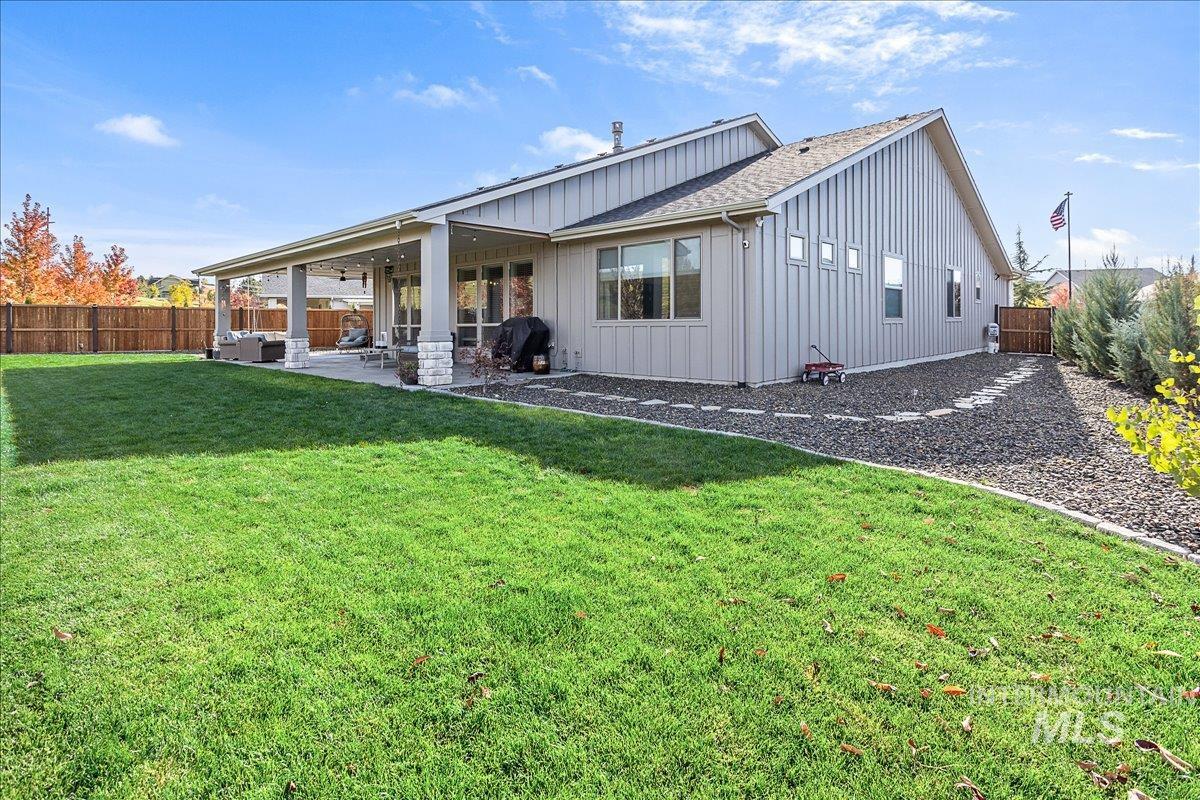 Rear view of house with a patio area, a fenced backyard, board and batten siding, and a shingled roof