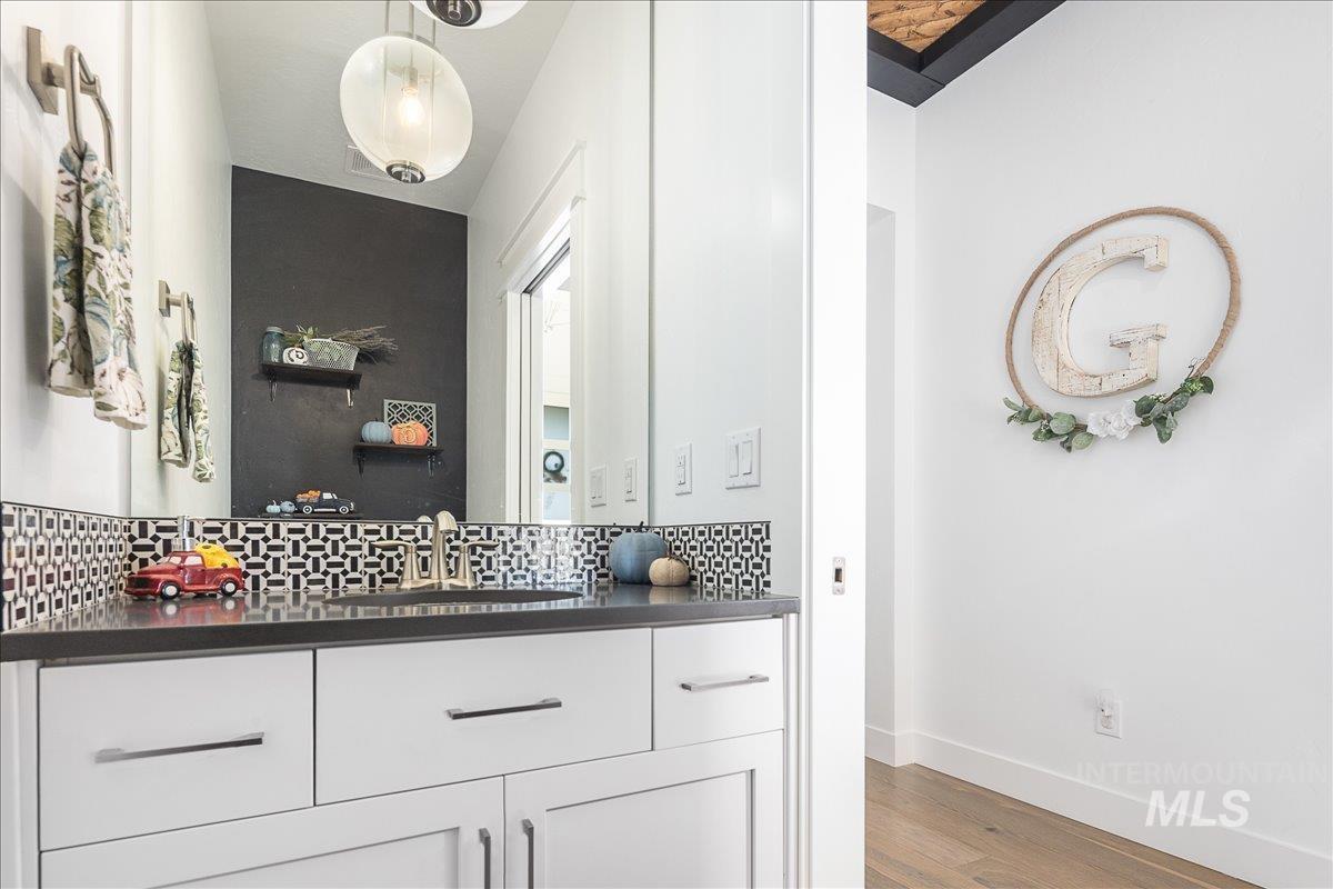 Bathroom featuring wood finished floors, vanity, and backsplash