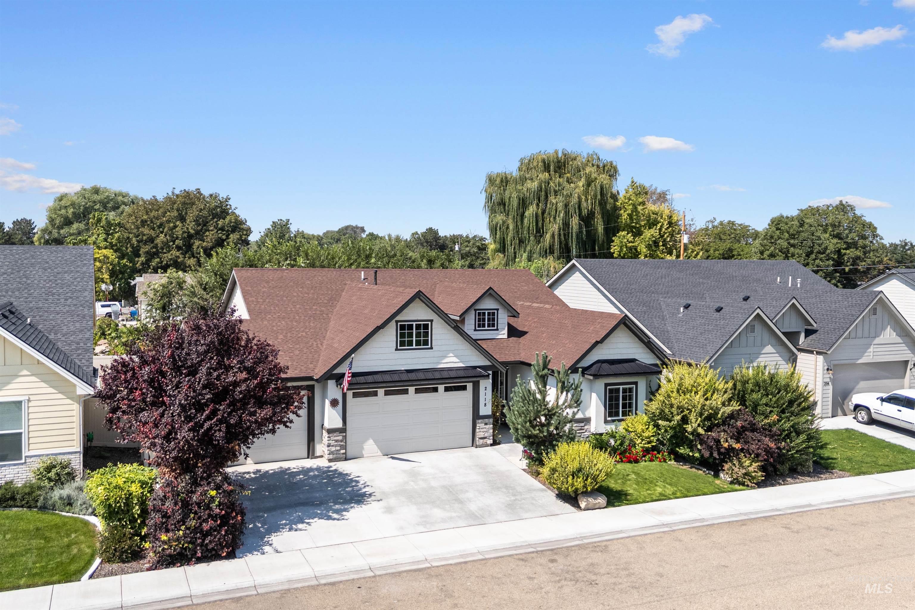 Traditional home with a shingled roof, concrete driveway, stone siding, a standing seam roof, and an attached garage