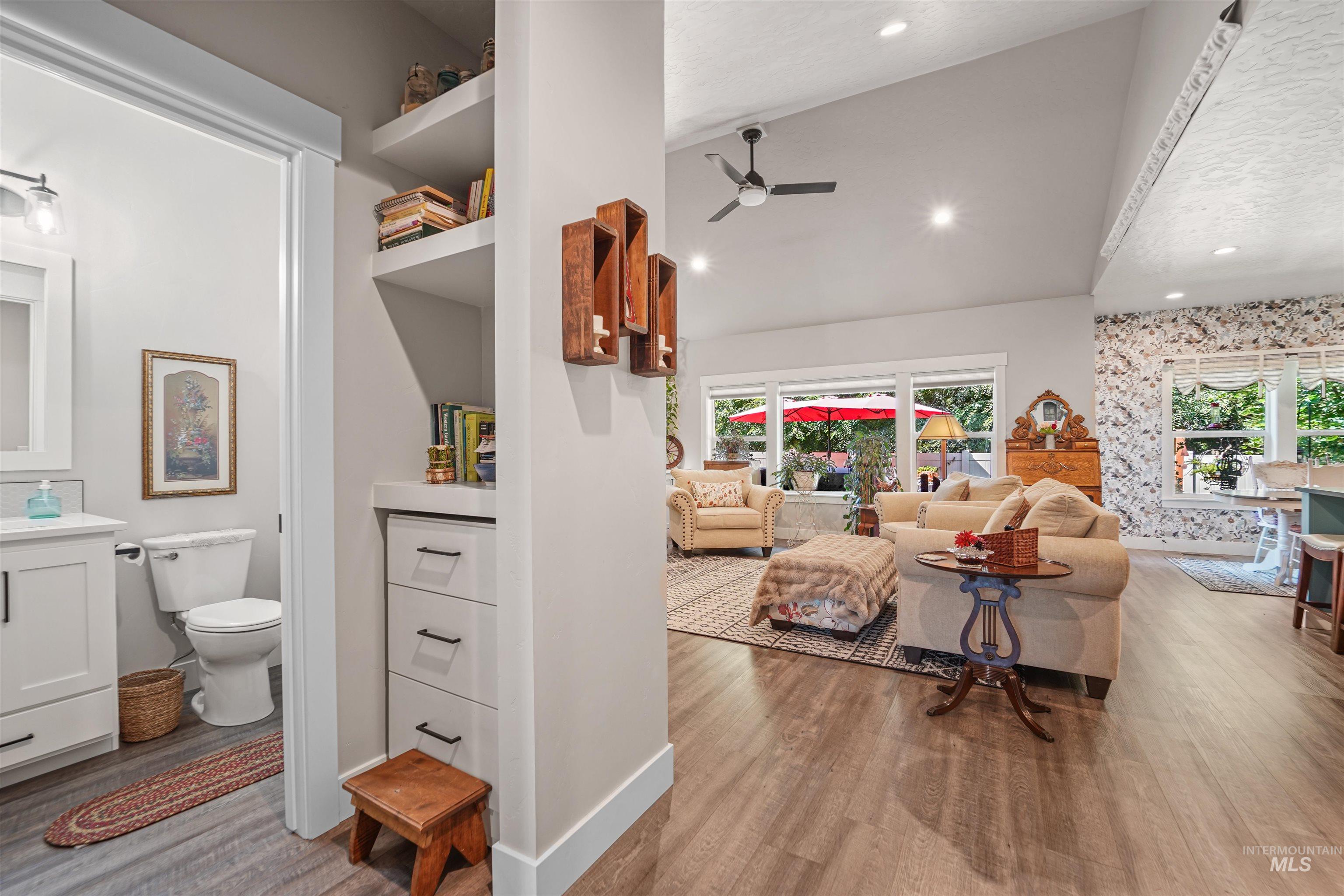Living room with light wood-type flooring, a ceiling fan, recessed lighting, and high vaulted ceiling