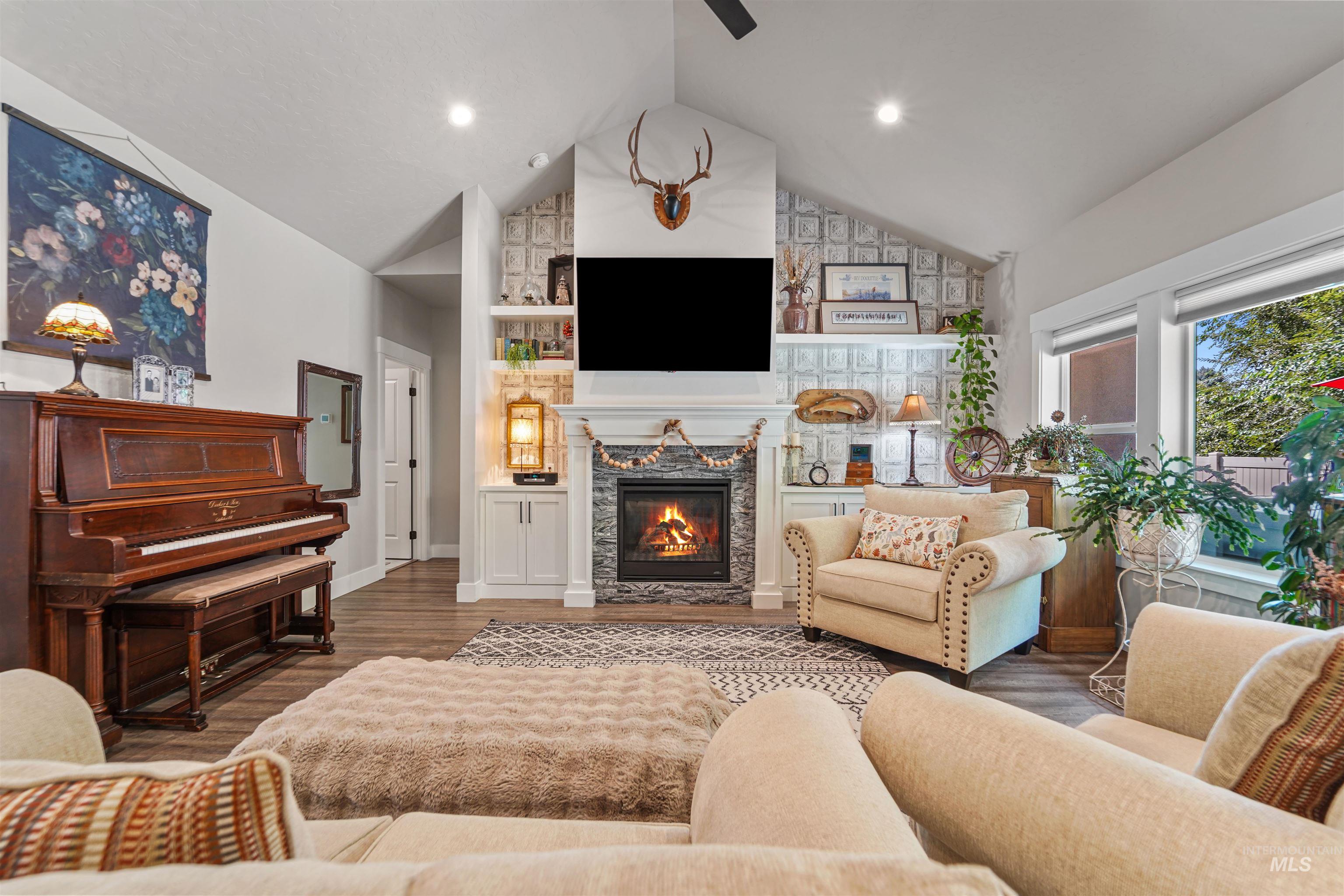 Living room featuring high vaulted ceiling, wood finished floors, a stone fireplace, recessed lighting, and a ceiling fan
