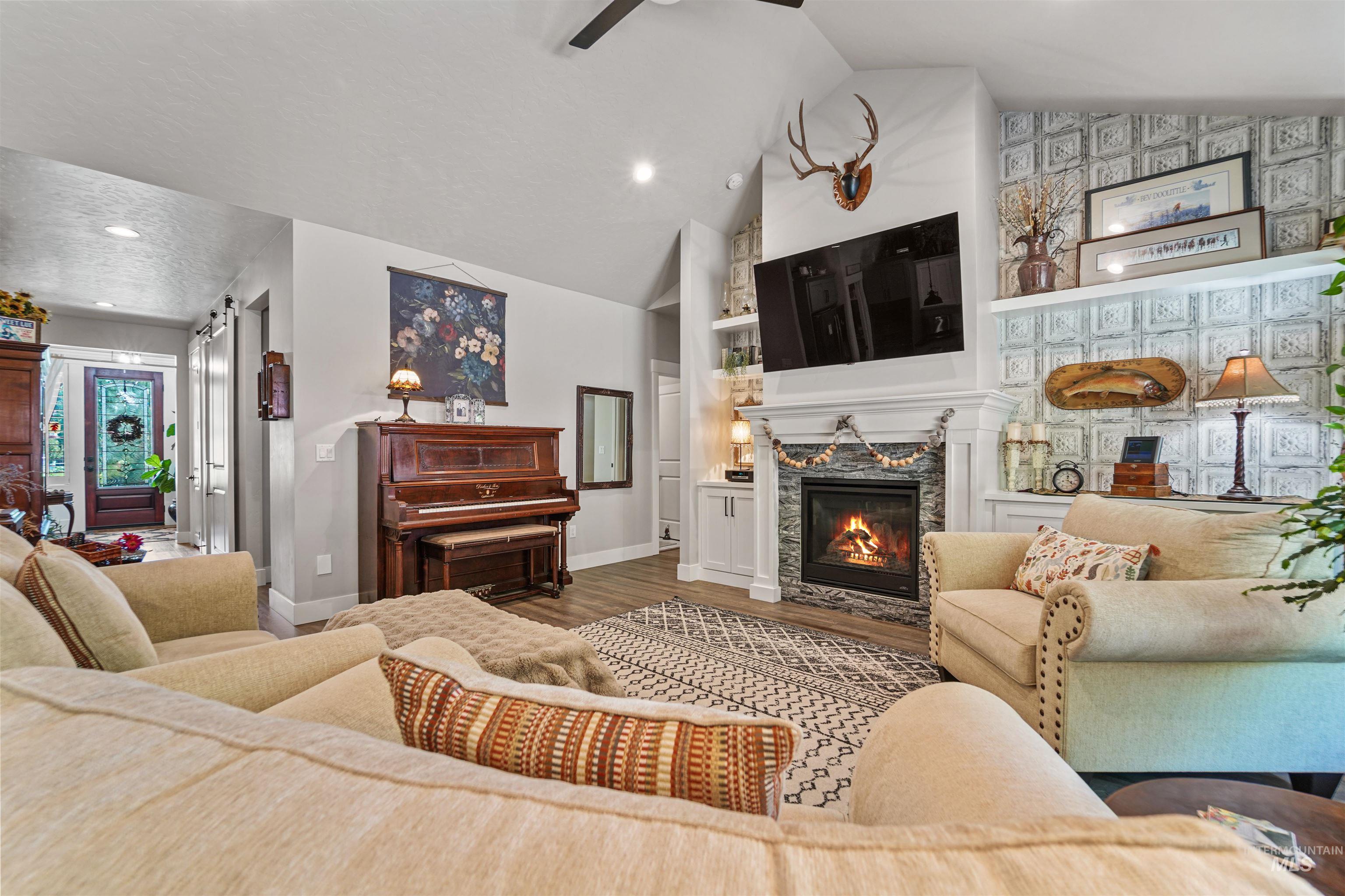 Living area featuring a glass covered fireplace, wood finished floors, high vaulted ceiling, and recessed lighting