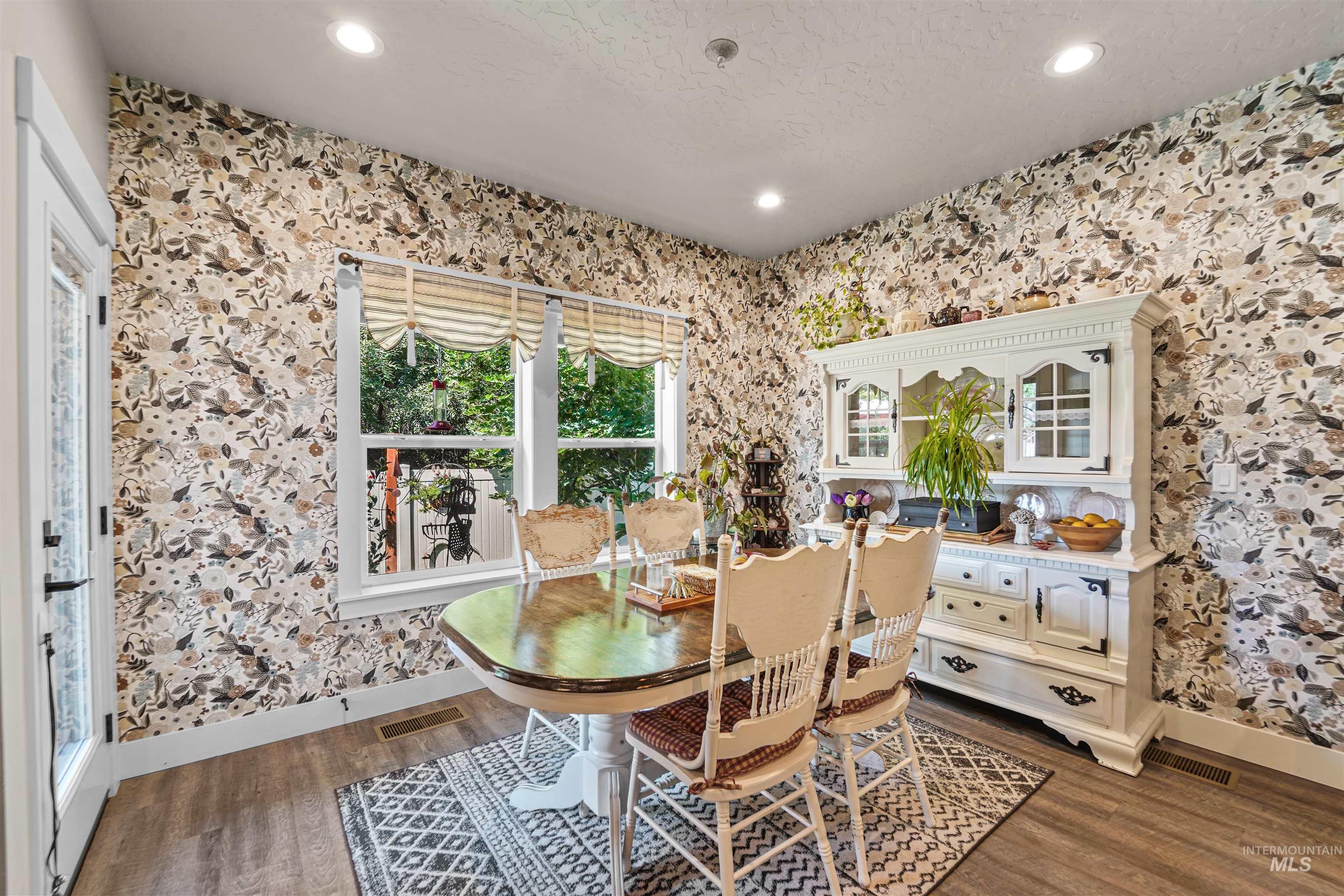 Dining space featuring wallpapered walls, dark wood-style flooring, and recessed lighting