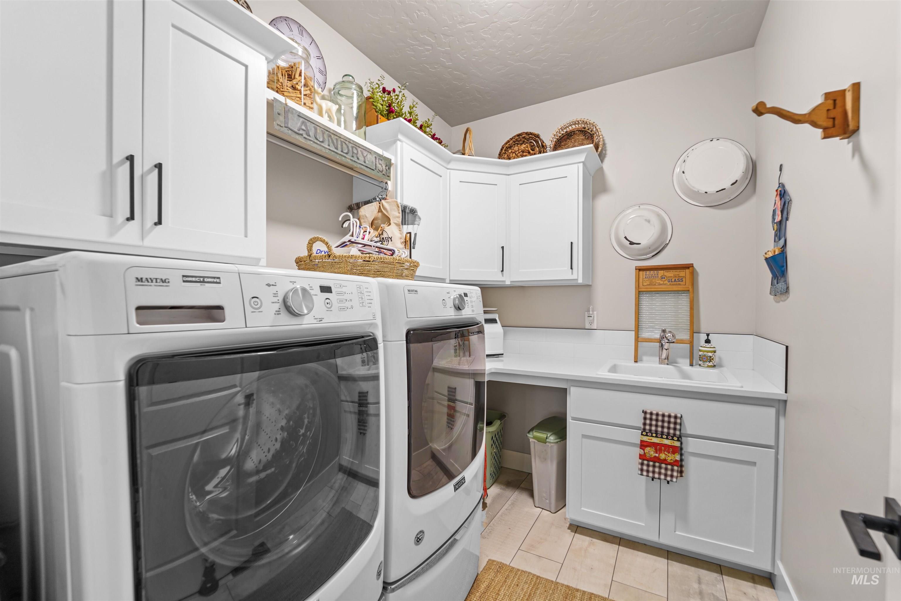 Laundry area featuring a textured ceiling, cabinet space, and washing machine and clothes dryer