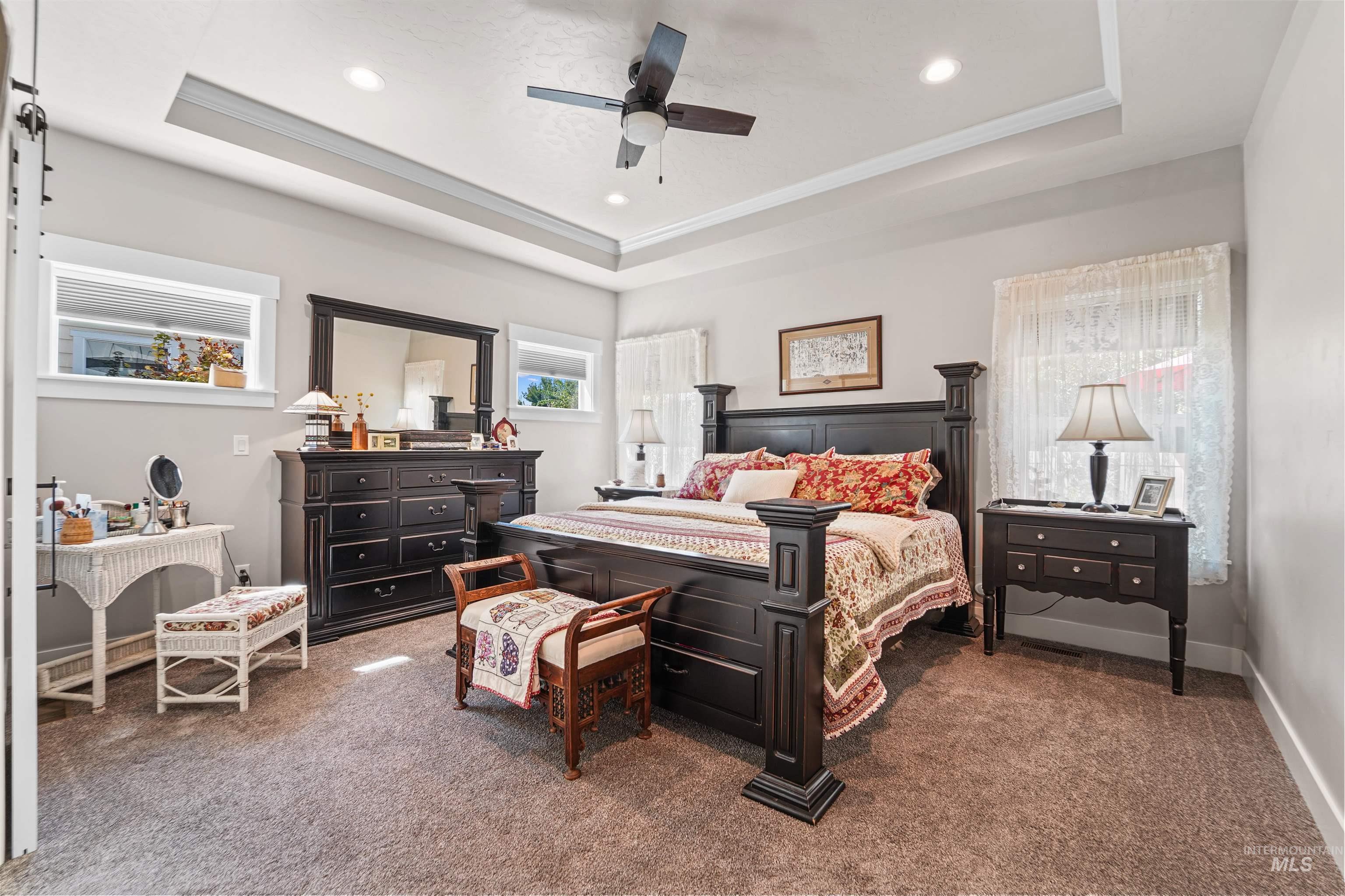 Bedroom with a tray ceiling, dark colored carpet, a ceiling fan, recessed lighting, and crown molding