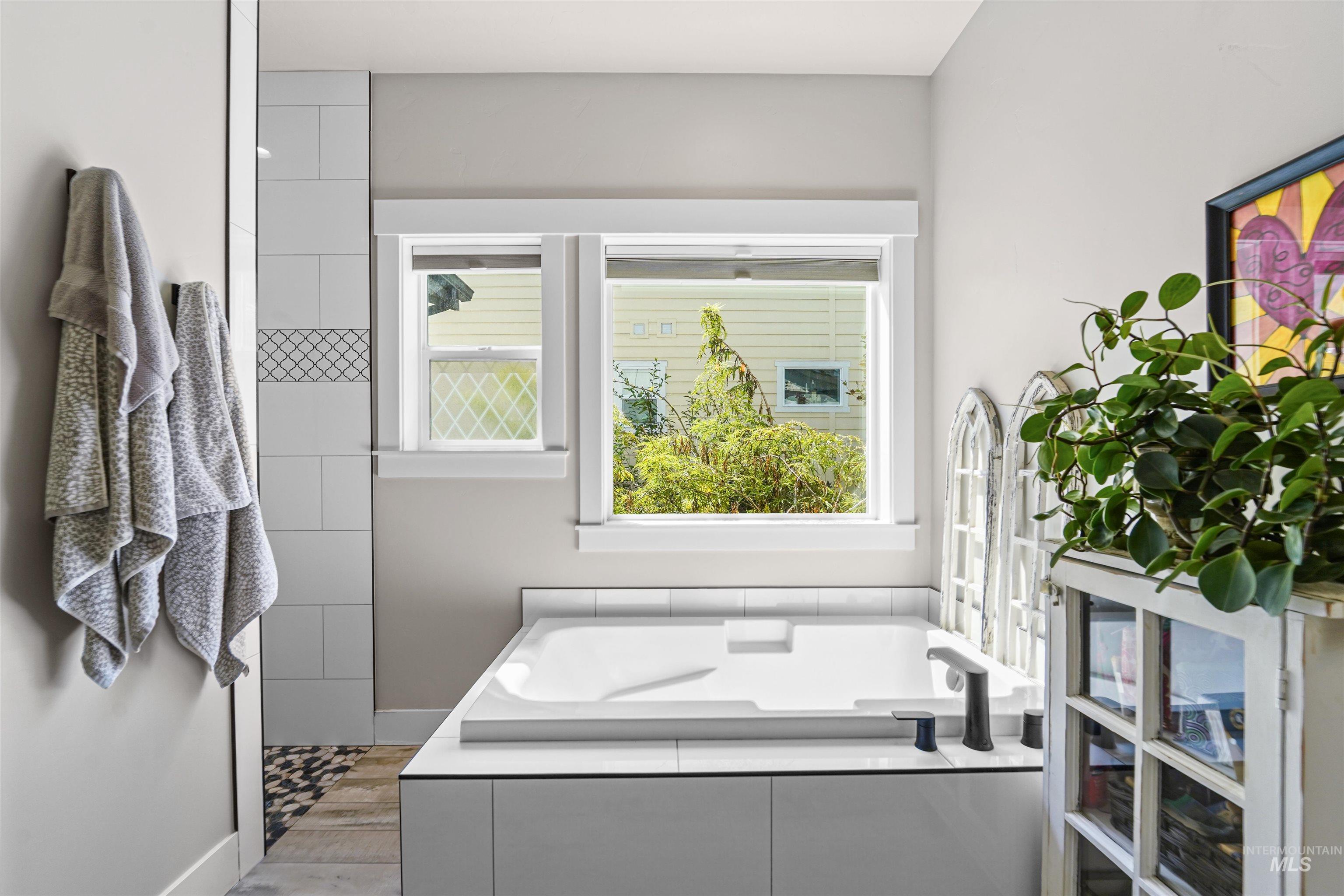 Full bath with a garden tub and baseboards