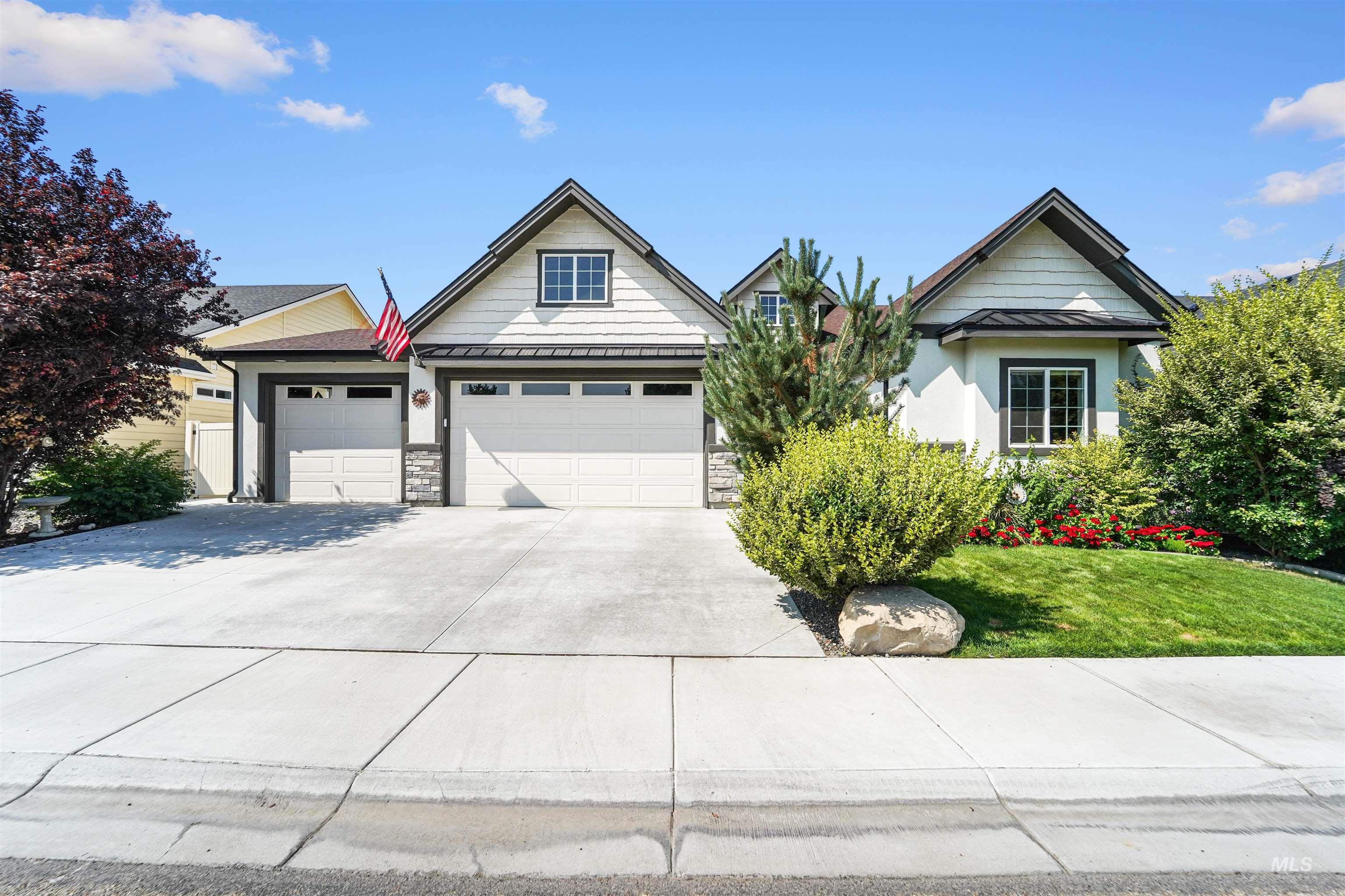 View of front of house featuring driveway, stucco siding, a standing seam roof, a front lawn, and a metal roof