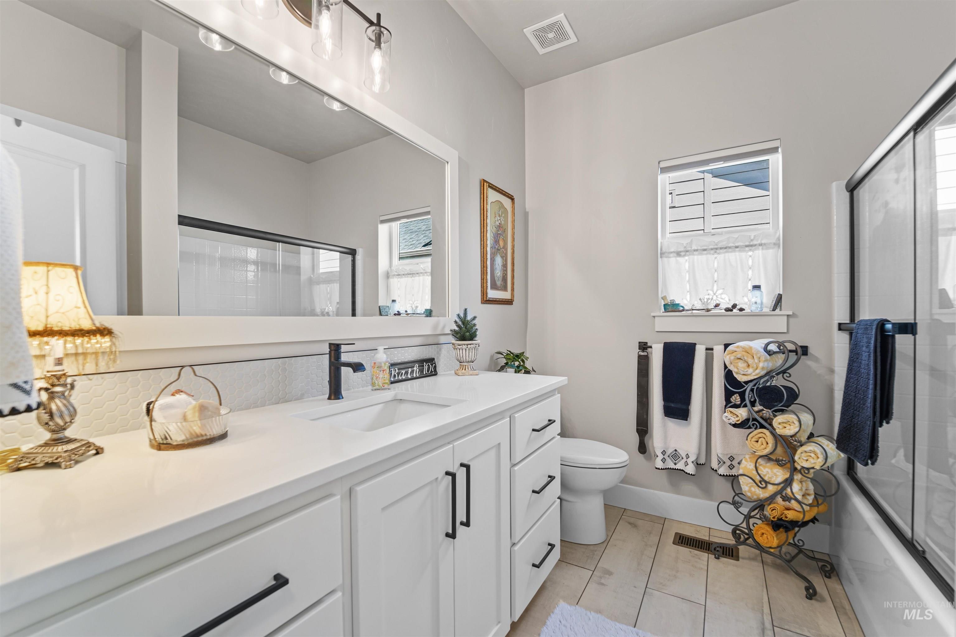 Full bath featuring vanity, bath / shower combo with glass door, and light wood-type flooring