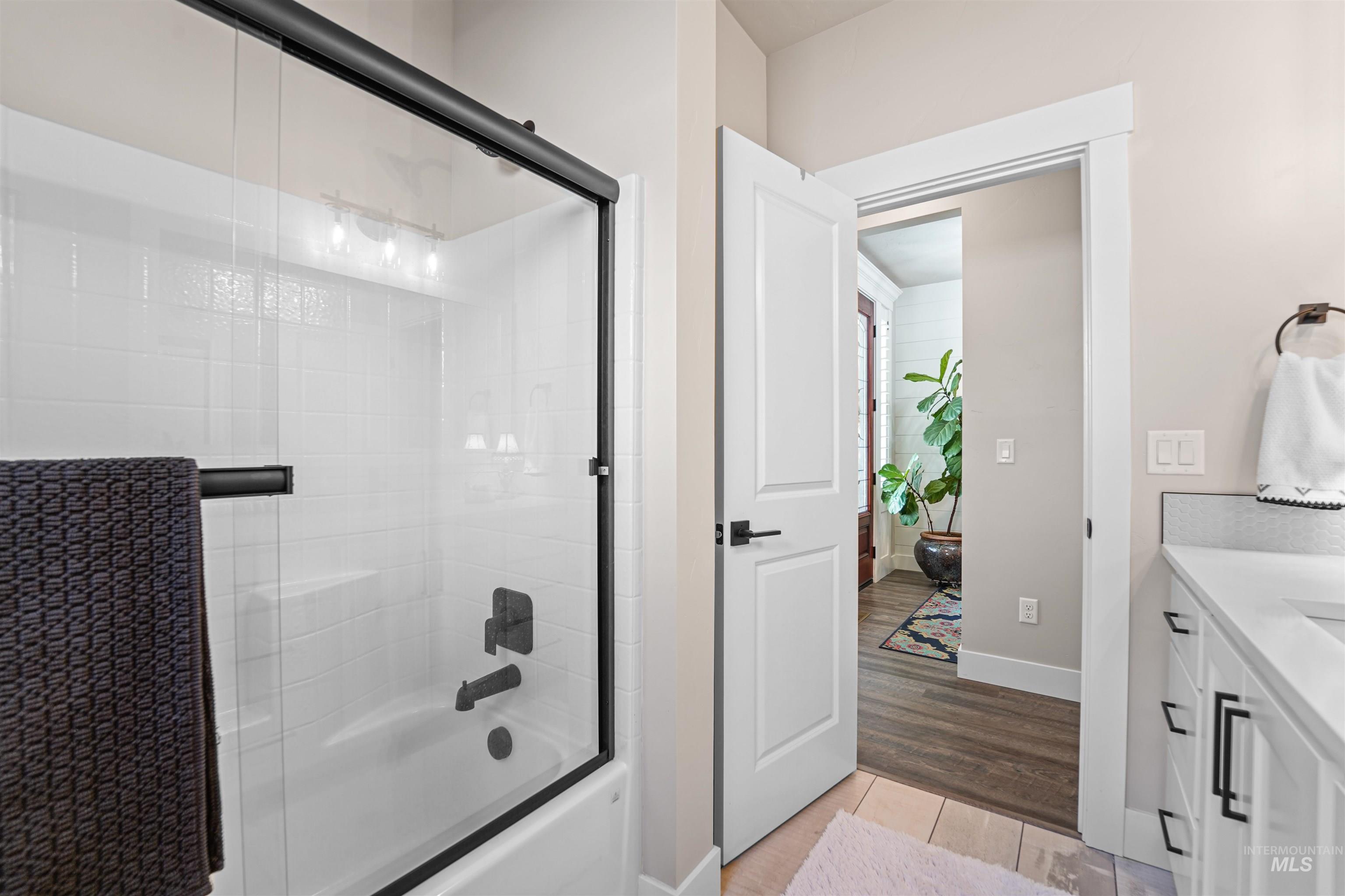 Bathroom with vanity, enclosed tub / shower combo, and light wood-style floors