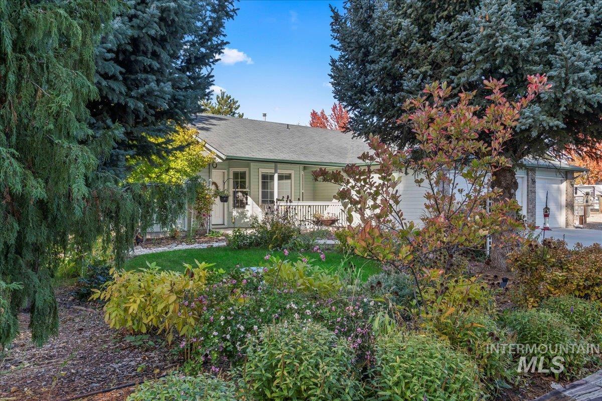 View of property hidden behind natural elements featuring a shingled roof