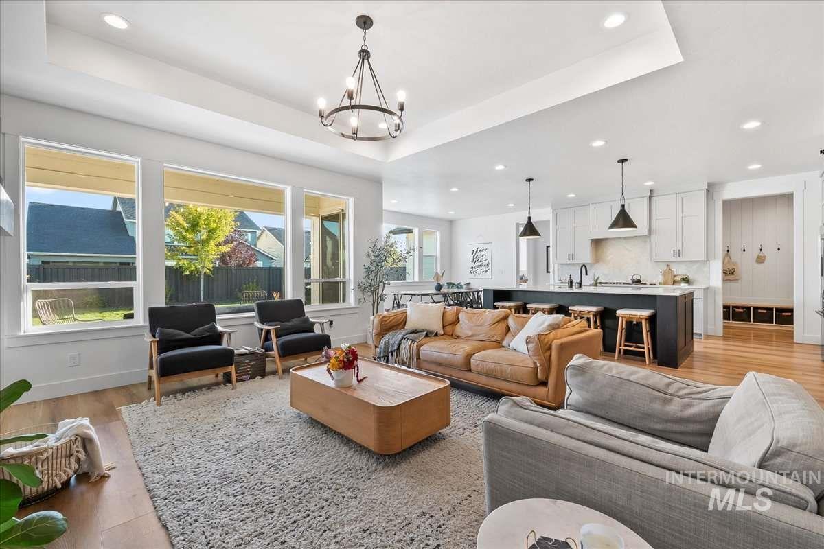 Living area featuring a tray ceiling, light wood-style flooring, recessed lighting, and a chandelier