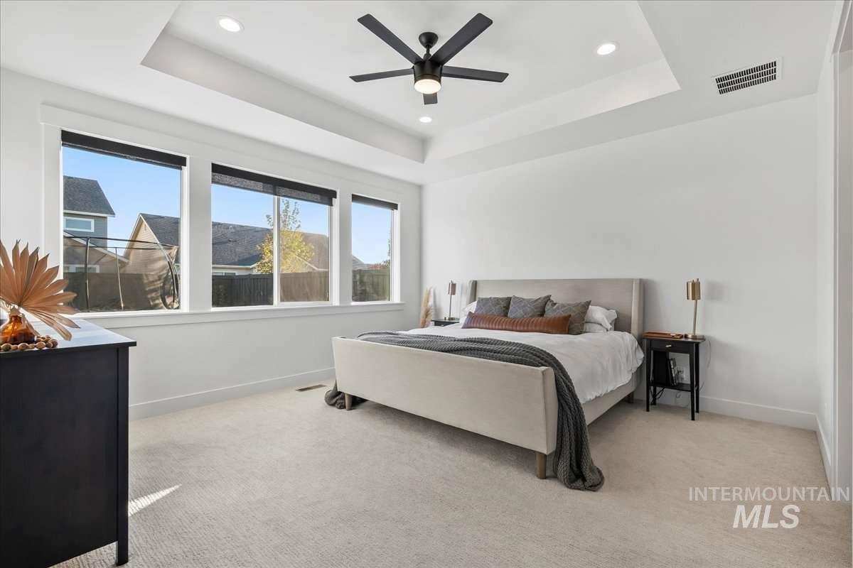 Bedroom featuring a tray ceiling, light carpet, a ceiling fan, and recessed lighting