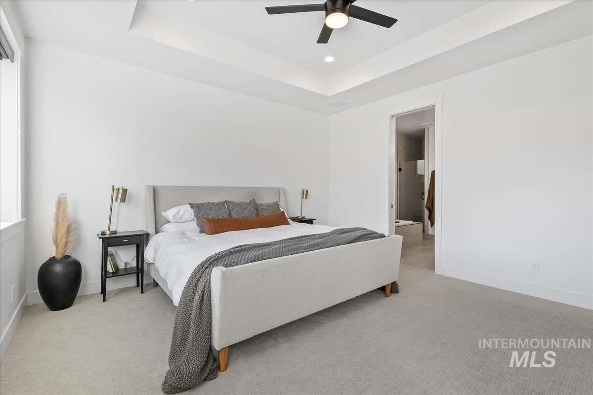 Bedroom featuring a raised ceiling, light colored carpet, a ceiling fan, and recessed lighting
