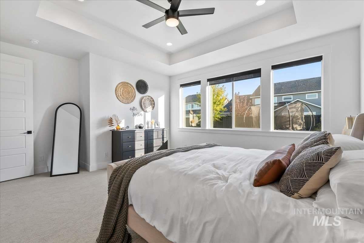 Bedroom with a tray ceiling, carpet, ceiling fan, and recessed lighting