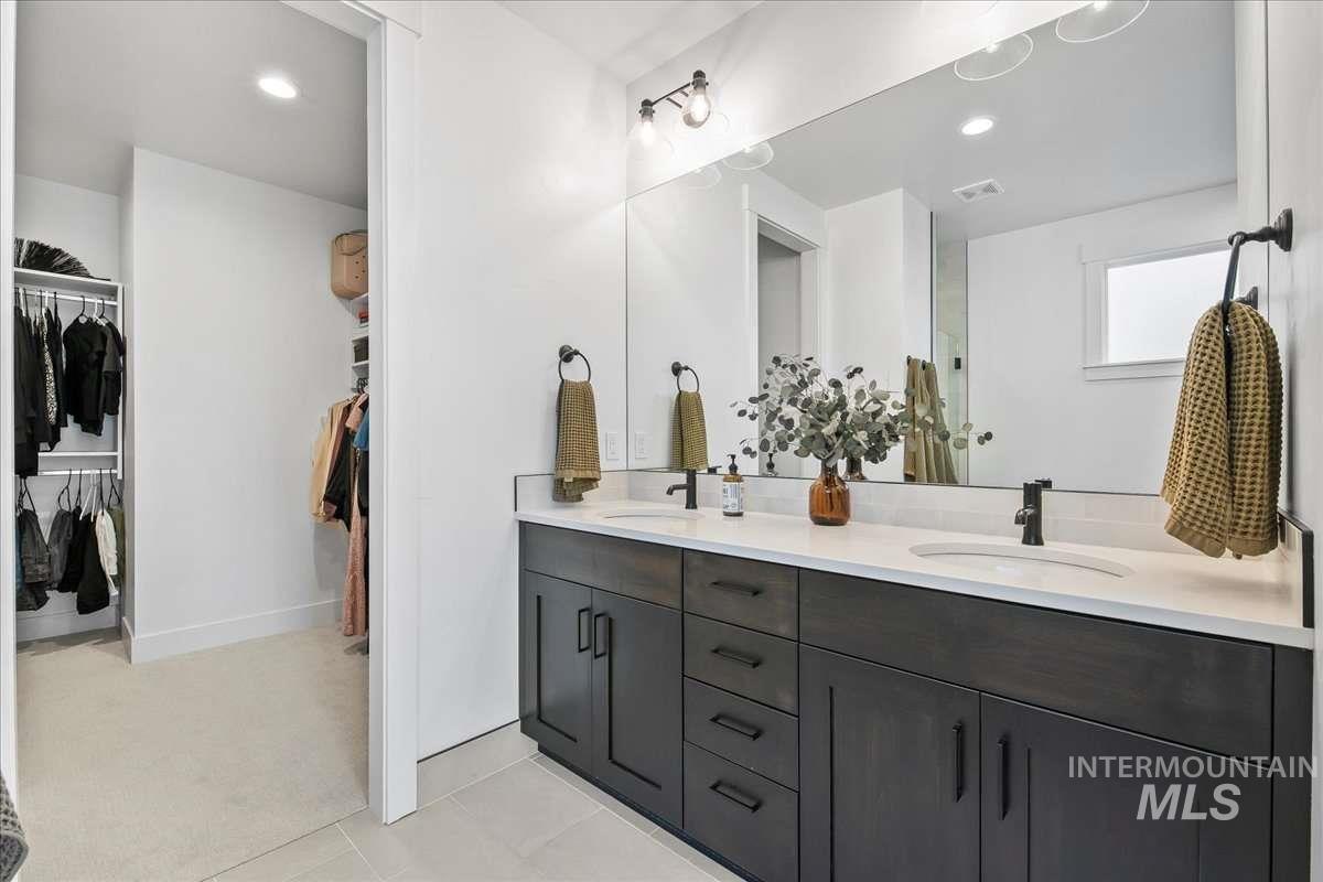 Bathroom featuring a spacious closet, double vanity, light tile patterned floors, recessed lighting, and light colored carpet