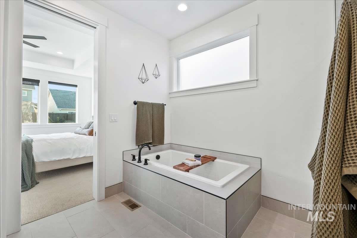 Full bathroom featuring ensuite bathroom, a bath, light tile patterned flooring, light carpet, and recessed lighting
