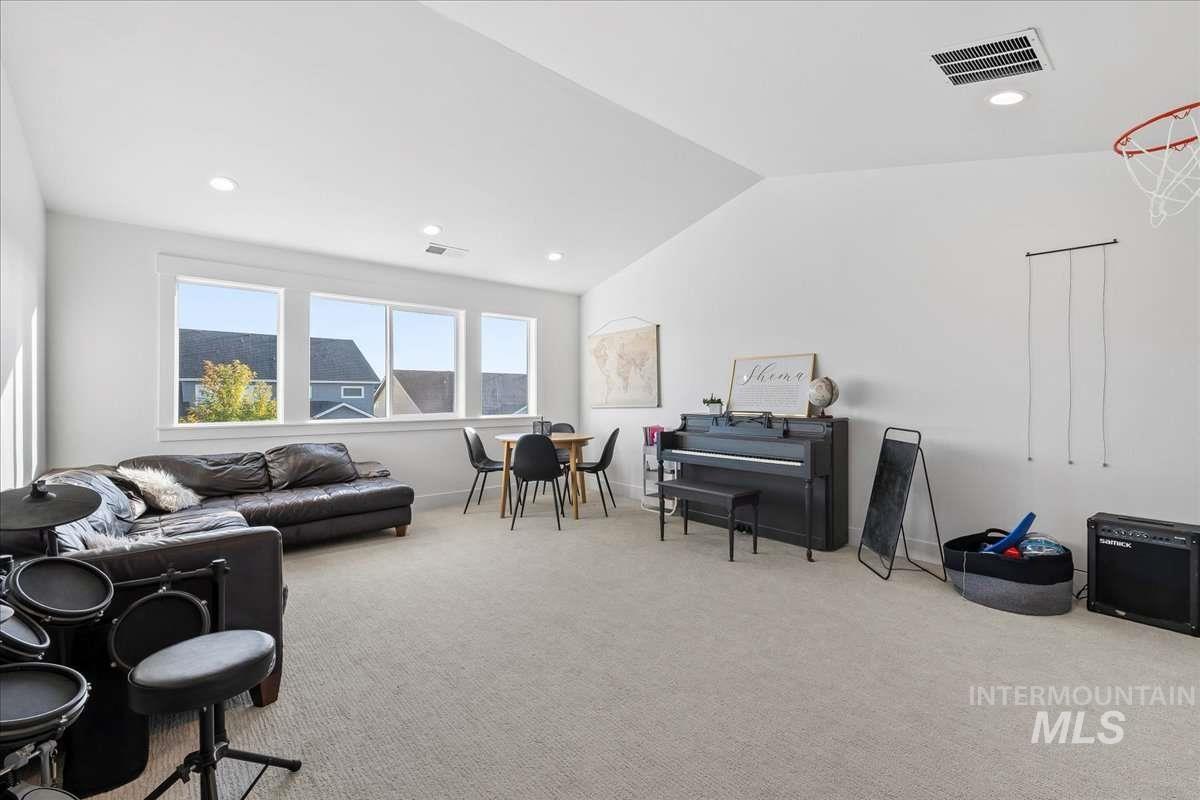 Living area with vaulted ceiling, light colored carpet, and recessed lighting