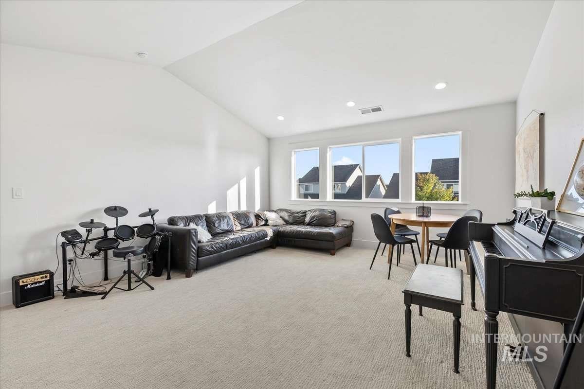 Living area with vaulted ceiling, light colored carpet, and recessed lighting